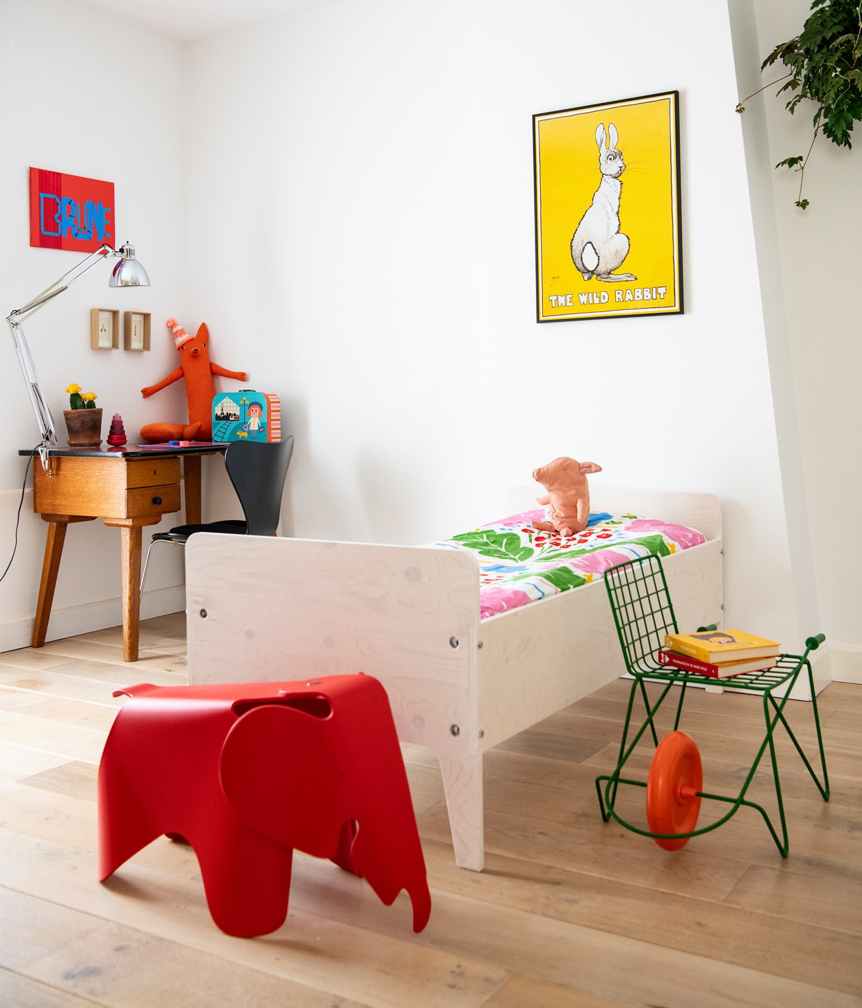 Kunstwerk Brune van Jochem Rotteveel. Bureau vintage, lamp Naska Lora van FontanaArte, knuffel vos Donna Wilson, kartonnen koffer Ingela P. Arrhenius, zwarte vlinderstoel Fritz Hansen. Bed Crisis van Piet Hein Eek, dekbedovertrek Onni van Marimekko, knuffel big Maileg. Poster The wild rabbit via Catawiki. Rijdende kinderstoel Trotter van Magis. Rode Eames-olifant Vitra.