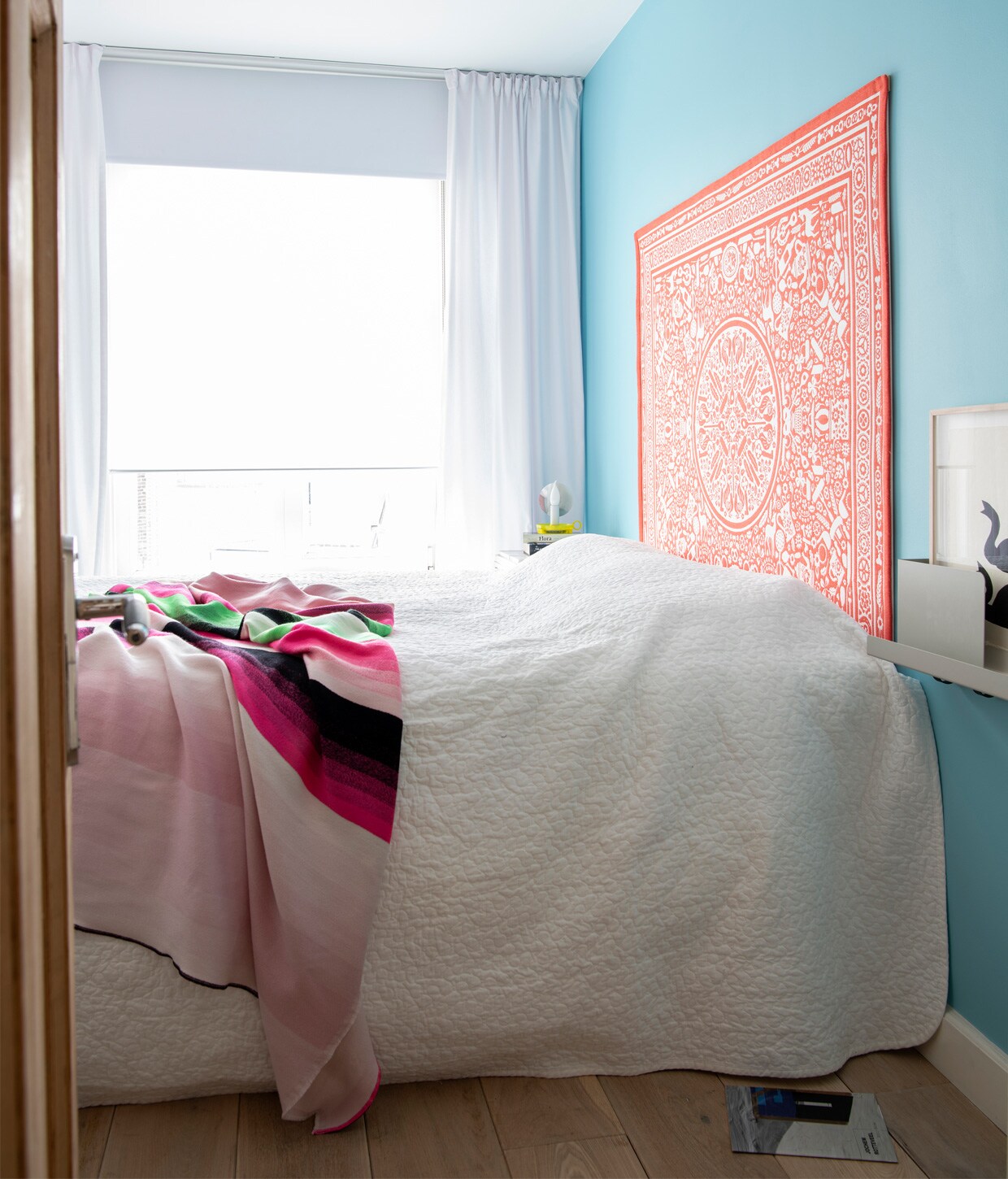 Muurverf gemengd bij Bierens Den Haag. Wit dekbedovertrek Ikea, plaid Hay. Gele lamp Flos. Oranje wandkleed Folklore Studio Job. Wandplank Folded Muuto.