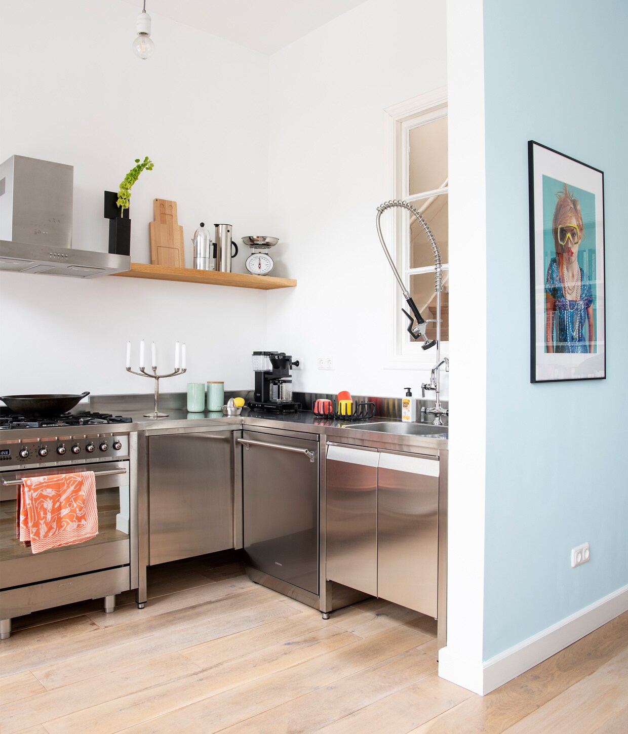 Muurverf gemengd bij Bierens Den Haag. Keuken en kraan Gastrosteel, oven Smeg, theedoek Studio Job. Zwarte vaas Passe partout van Cor Unum, houten snijplank Piet Hein Eek, koffiemachine Alessi, thermosfles EM77 Vacuum van Stelton, Herkomst weegschaal onbekend. Kandelaar Lucy van Marcel Wanders, koffiemaker Moccamaster. Kunstwerk aan de muur Lois van The Frozen Fountain.
