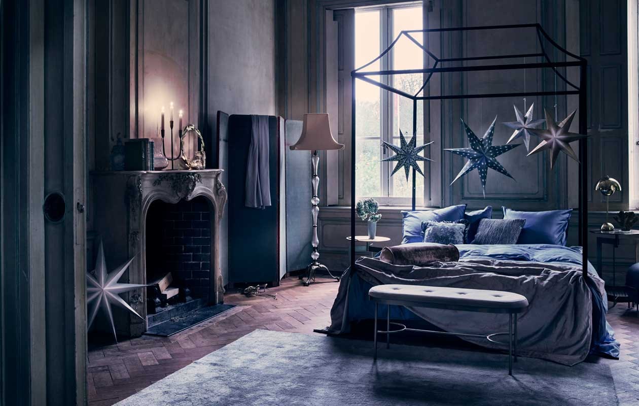Hemelbed, op maat gemaakt, prijs op aanvraag (com-anders.nl). Fluwelen bank € 199,-, grijs wolmix vloerkleed, 240×170 cm € 299,- (hm.com). Kamerscherm € 600,-, schemerlamp, prijs op aanvraag (pietjonker.nl). Goudkleurige bijzettafels, set van 2 € 400,-, fluwelen kussen met ribbels € 36,95, fluwelen rolkussen € 33,33 (nordal.eu). Lichtgrijze fluwelen sprei € 195,- (mlfabrics.nl). Satijnen dekbedovertrek Stone Blue, 220×240 cm € 139,-, kussensloop 50×70 cm € 19,95 (suite207.com). Goudkleurige leeslamp Flowerpot van &amp;Tradition € 300,- (kasstoor.nl). Driearmige kandelaar € 49,95, vaasje op bijzettafel € 49,95 (maisonnl.com). Grote zilverkleurige waxinelichthouder € 19,50, kleine waxinelichthouder € 8,95 (weldaad.com). Goudkleurige krans van blaadjes € 51,99, grote ster 80 cm € 35,-, medium blauwe ster € 20,-, kleine blauwe ster € 10,75, kleine zilveren ster € 10,75, medium goud met witte ster 60 cm € 20,-, lila glazen karaf op schouw € 35,- (bungalow.dk). Poef Macaron van Bolia € 377,99 (vtwonen.nl). Overig privébezit.