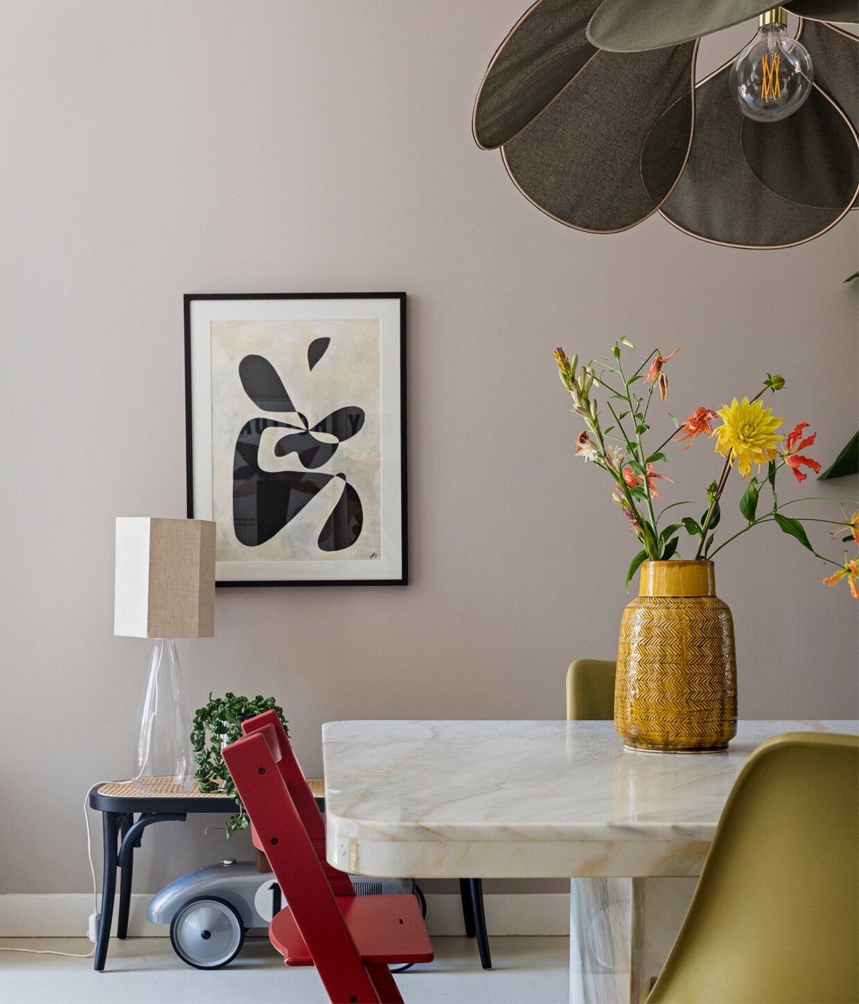 Kunstwerk Cate Adriana, glazen tafellamp en eetkamerstoelen Casa Gitane met kap van HKliving, rotan bankje Westwing, speelgoedauto gekregen, rode kinderstoel Stokke, tafel Marktplaats, gele vaas Leen Bakker, groene lamp Rockett St George.