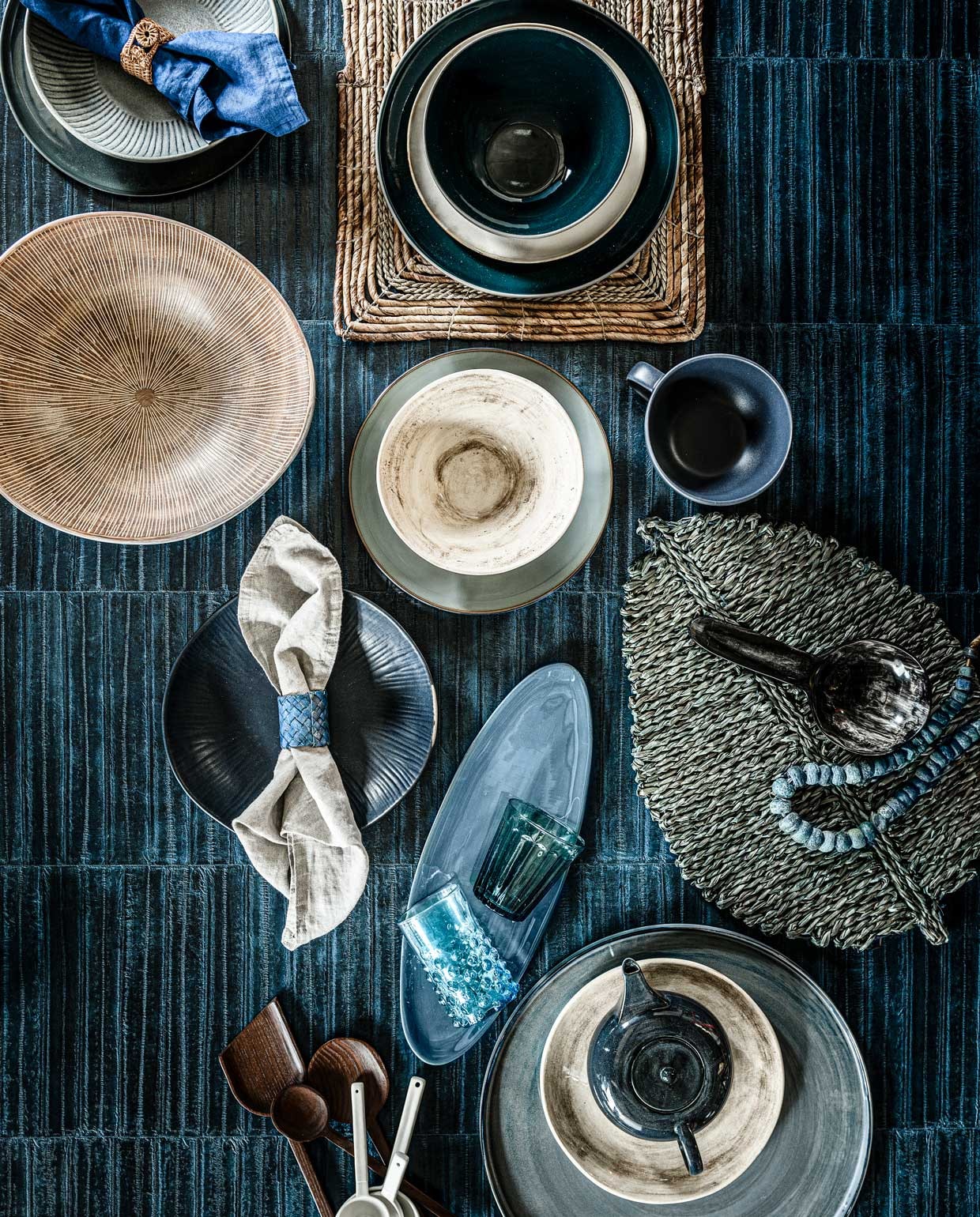 Behang Anguille uit de Anguille Big Croco Galuchat-collectie van Elitis, rol 1×10 m € 212,- (loggerewilpower.com). Vergrijsd blauw diep bord met streeptextuur € 7,99, blauw linnen servet per 2 € 9,99, beige linnen servet, per 2 € 9,99 (hm.com). Jeansblauw bord met zwarte rand van Serax € 24,70, diepblauw glanzend bord van Serax, Ø28 cm € 41,-, effen beige glanzend bord van Serax € 13,55, diepblauwe glanzende kom van Serax € 30,-, jeansblauw glanzend bord van Serax € 24,70, jeansblauw XL bord van Serax, Ø36 cm € 99,- (vtwonen.nl). Beige schaal met strepen € 89,- (covanderhorst.nl). Beige-bruine kom € 27,95, beige-bruin bord € 24,95, blauwe mok € 9,- blauw ovaal bord € 16,95, mat donkerblauw bord € 27,95, felblauw glas € 10,-, donkerblauw glas € 10,-, witte porseleinen lepels, per stuk vanaf € 7,95 (paviljoennoord.com). Rotan bladvormig dienblad € 9,95, rotan dienblad € 6,50, hoornen lepel € 9,90 (loods5.nl). Theepot € 39,- (klevering.com). Houten lepels, per 4 € 65,- (fermliving.com). Servetringen, per 4 vanaf € 14,99 (zarahome.com). Antieke glazen kralenketting uit Nigeria € 435,- (couleurlocale.eu).
