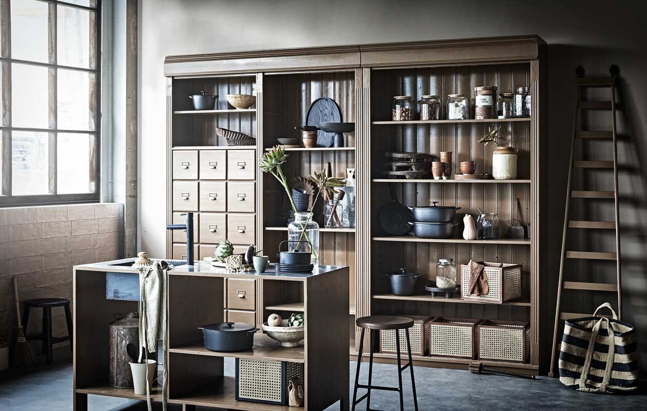 Antieke kast en op maat gemaakt keukeneiland met spoelbak prijs op aanvraag (com-anders.nl). De kast is geschilderd met matte lak op waterbasis in Praline van Pure &amp; Original, per liter € 57,25 (deruamsterdam.nl). Barkruk van Hay € 199,-, theepot Collage van Serax € 88,-, keukengerei Pure van Serax, set van 5 € 53,-, ovaal dienblad Vincent Van Duysen van Serax € 89,-, kookpan Surf van Serax in keukeneiland, 5,5 liter € 190,-, bruin bord Urban Culture Nature, Ø 26 cm € 18,35, bruinekom Urban Culture Nature, Ø 12,5 cm € 12,75, zwartbord Urban Culture Nature, Ø 22 cm € 16,35 (vtwonen.nl). Voorraadpotten met houten deksel Ikea 365+ serie € 8,99, zwarte metalen braadpannen Vardagen vanaf € 44,95, poffertjespan Vardagen € 22,95, ronde pan met deksel Vardagen vanaf € 39,95 (ikea.nl). Grote glazen vaas € 33,50 (weldaad.com). Papier-maché schalen in zand en geel € 37,-, lage zwarte kruk € 10,- (nordal.eu). Rattan opbergboxen € 39,99, houten dienblad op pootjes € 29,90 (hm.com). Muurverf Mire van vtwonen, per liter € 18,99, schort € 22,50, bamboe bezem € 13,75, houten dienblad in kast € 55,25, houten serveerschaal € 21,50 (vtwonen nl). Overig privébezit.