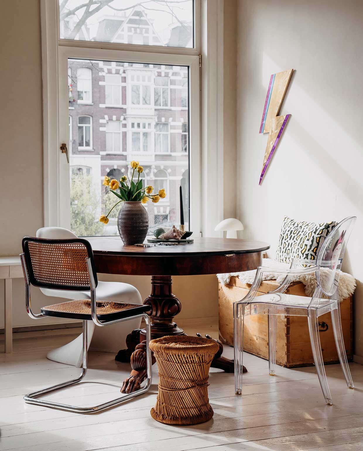 Tafel, kist en vaas, erfstukken. Tafellamp Night Owl van Lightyears. Krukje Marktplaats. Witte stoel Verner Panton van Vitra, transparante stoel Louis Ghost van Kartell, zwarte stoel vintage. Foto aan de wand uit de serie ‘Paula’ van Hendrik Kerstens. Bliksemschicht via Bride &amp; Wolfe. Vachtje gekocht op Noordermarkt. Kussen Living Stories.