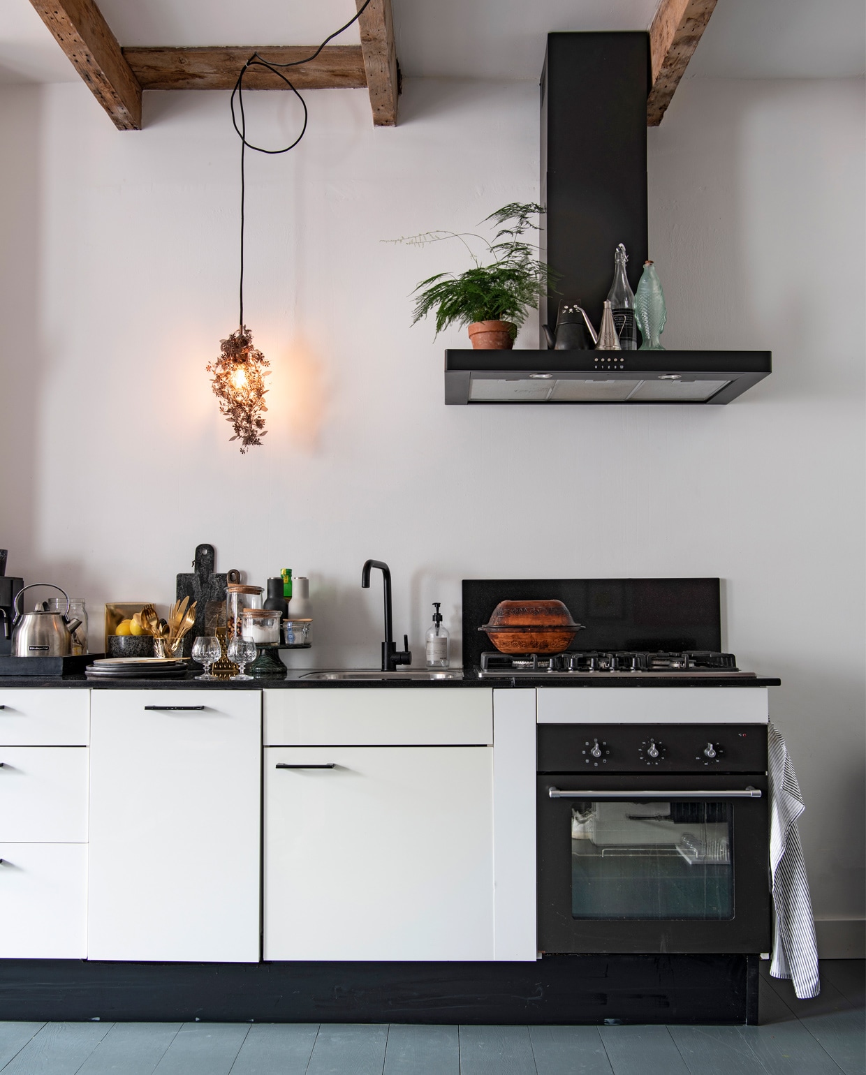 Keuken en oven Ikea, afzuigkap Smeg. Glazen vis van Paola Navone voor Serax, hanglamp Garland Bronze van Tord Boontje, cooker KitchenAid. Zwarte broodplank Menu, bruine broodplank H&amp;M. Rasp Bloomingville, voorraadpotten en vijzel tweedehands, bestek en theepot Urban Outfitters, zwarte borden Esrum van Broste Copenhagen. Glazen oliefles souvenir uit Frankrijk.