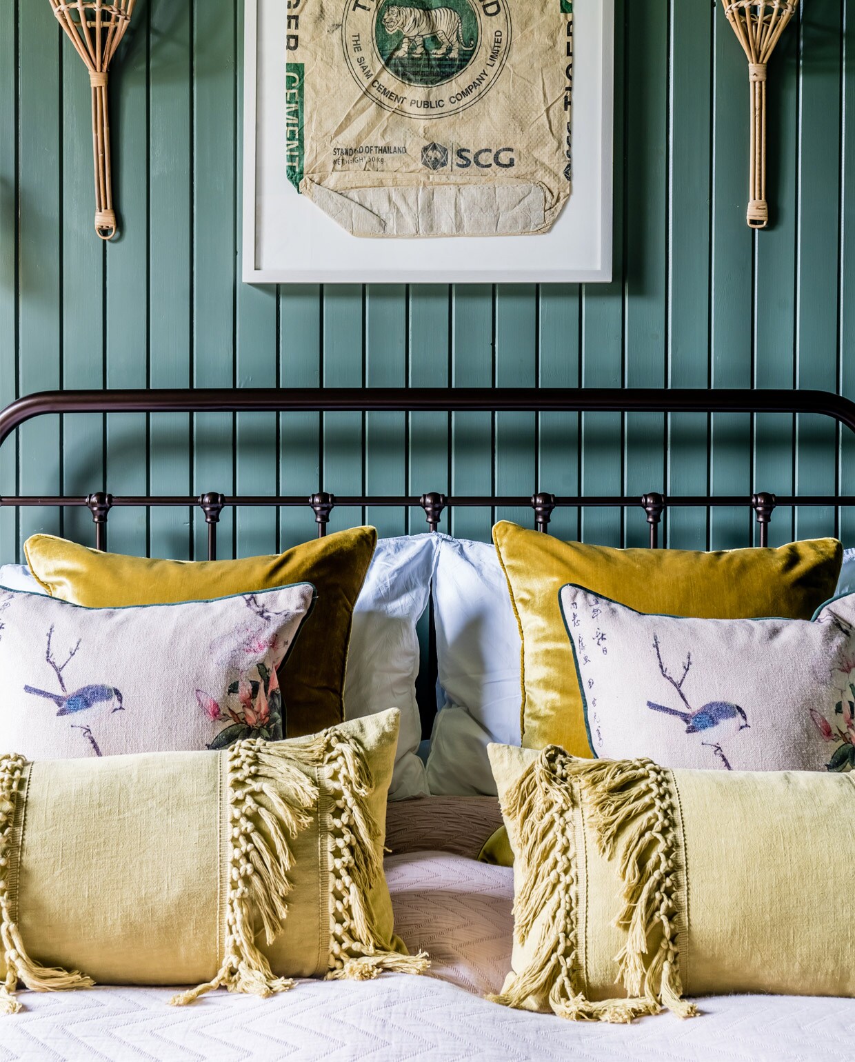 Bedframe kopie van een Victoriaans model. Vloerkleed Urban Outfitters. De ingelijste print is een cementzak uit Birma, de twee objecten aan weerszijden zijn fruitvangers.