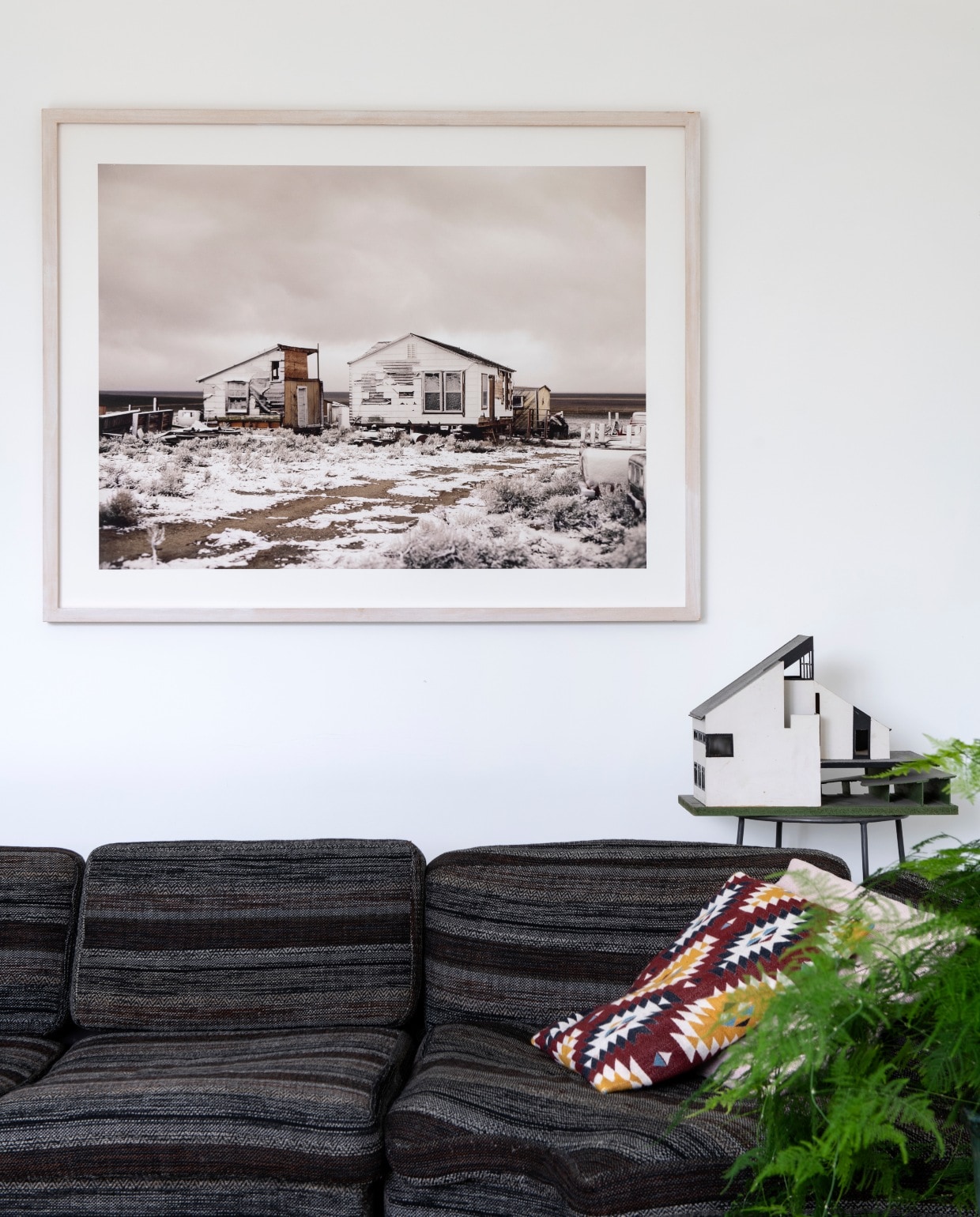 De foto van Roderik Henderson is een cadeau van Clementine haar ouders. Jaren 70 Artifort bank gekocht op Catawiki. Roze kussen Linum. Ikat-kussen en vloerkleed Ikea. Hoog stalen tafeltje Wereldwinkel met een maquette van ouderlijk huis.