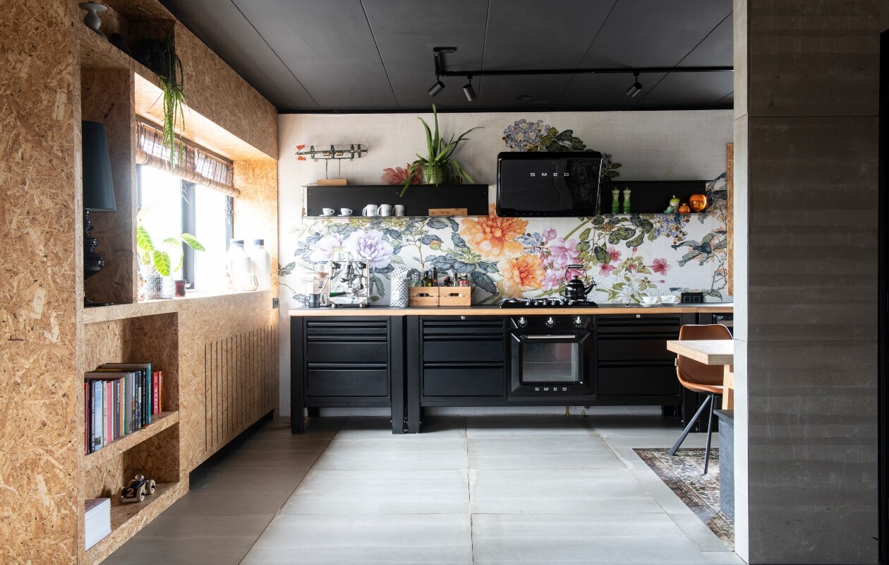 Modulekeuken en keuken – planken via The Big Eeasy Kitchen. Spatwand-behang Kitchen Walls via Behangfabriek. Kast door Rein gemaakt met osb-platen. Stoel Franky Chair van Dutchbone. Vinyl kleed met antisliplaag, zwarte tafellamp en plafondspots Slowclub, wit aardewerk op plank van Rocket, Espresso en Vascobelo. Witte keramieken vazen Royal Delft. Auto in kast Floris Hovers. Lamp op kast gemaakt door Rein van oude Meccano. Groen peper en zoutstel en ketel op fornuis Le Creuset. Espressomachine Rocket.