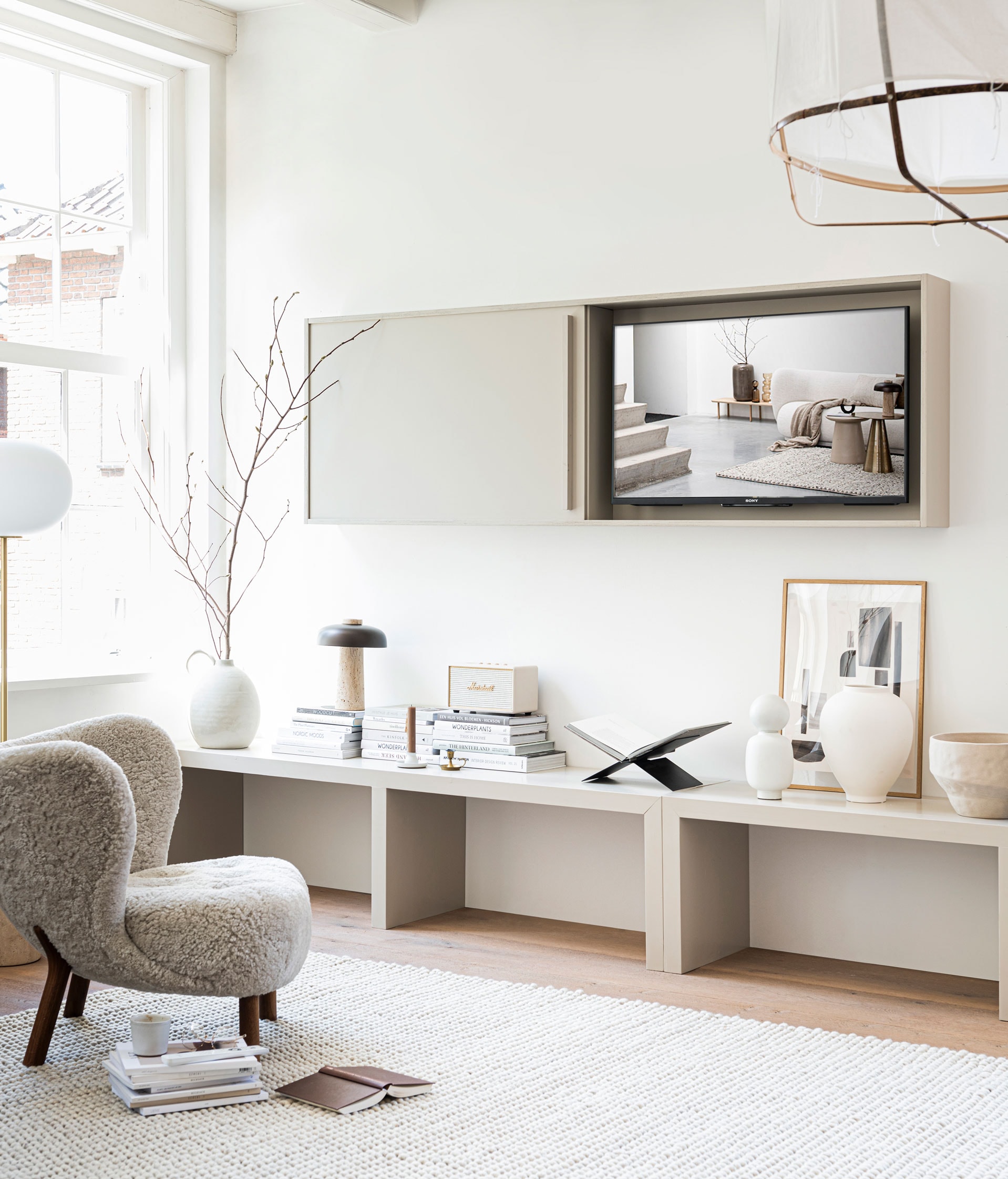 Fauteuil Little Petra van &amp;tradition € 2609,-, hanglamp van Ay illuminate € 429,- (flinders.nl). Vloerlamp JWDA met travertin voet € 1499,95, tafellamp met travertin voet en bronzen aluminium kap Reverse van Aleksandar Lazic € 550,- (menuspace.com). Vloerkleed Peas soft van Hay 300×200 cm € 935,-, witte vaas met boldop Muses Talia van Ferm Living € 79,- (vtwonen.nl). Vaas met oor en grote witte vaas vanaf € 45,99, aardewerken kom € 45,99 (zarahome.com). Zwarte stalen boekenstandaard € 45,- (mendo.nl). Poster Shapes, 140×50 cm € 47,75 (facade-apt.com). Eikenhouten frame A3-formaat € 54,95 (moebe.dk). Crèmekleurige wifi-luidspreker Marshall Acton € 274,- (coolblue.nl). Mok € 14,50 (suhka.nl). Verfkleur sidetable en tv-meubel Rolling Fog (littlegreen.nl). Sidetable op maat gemaakt, prijs op aanvraag (richardvanmeerveld.nl). Overig privébezit.