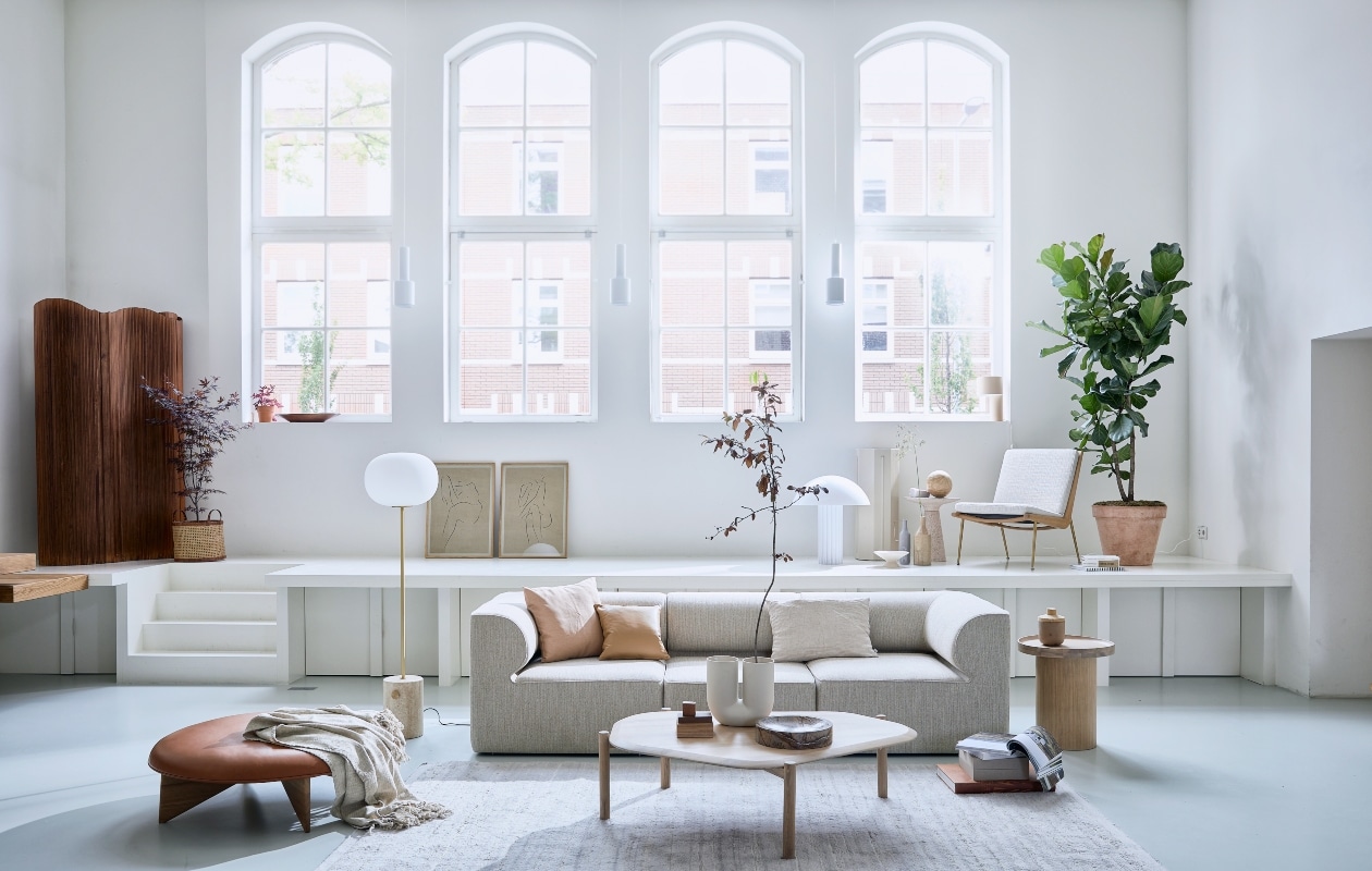 Elementenbank Eave van Menu Space, hoekelement vanaf 86x86x70,5 cm (lxbxh) € 1822,- midden-element vanaf 86x75x70,5 cm (lxbxh) € 1366,-, vloerlamp JWDA van Menu € 1499,95 (designtales.nl). Vloerkleed prijs op aanvraag (misterdesign.nl). Eikenhouten bijzettafel Plateau, 48×52,3 cm (Øxh) € 439,-, wit geoliede eikenhouten salontafel Island, 129x107x35 cm (lxbxh) € 999,-, leren kussen Classic, 40×40 cm € 272,- (bolia.com). Leren poef van Fogia, Ø 112 cm € 1635,-, fauteuil Boomerang van &amp;Tradition, 69x69x80 cm (lxbxh) € 2472,- (kasstoor.nl). Witte u-vormige vaas Kink van Muuto € 179,- (homestede.nl). Bijzettafel Victoria van Zuiver € 279,-, tafellamp Cupola van HKliving € 395,-, marmeren schaal Scapa van Ferm Living € 179,-, fruitschaal van HKliving € 29,-, vaas in zandtint Madam Stoltz € 34,50, langwerpige grijze vaas met handvat van vtwonen € 34,95 (vtwonen.nl). Stukjes hout (fijnhout.nl). Pilaar € 50,- (com-anders.nl). Posters Grace 1 en Grace 11 by lemon met eikenhouten frame, 50×70 cm € 90,- (papercollective.com). Zalmkleurige kussenhoes, 50×50 cm € 9,99 (zarahome.com), linnen kussen, 60×40 cm € 59,- (bymolle.com). Overig privébezit.