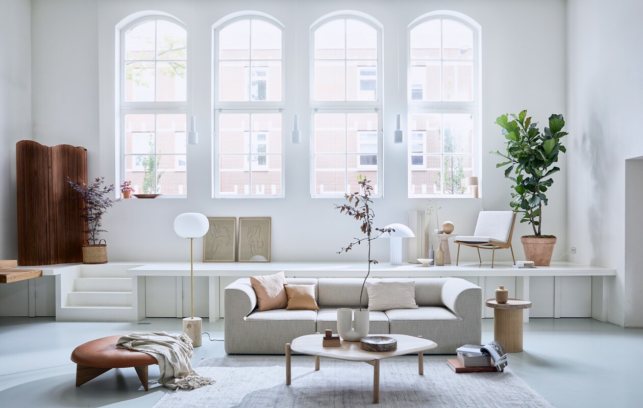 Elementenbank Eave van Menu space hoek element vanaf 86×70,5x86cmlxhxb€ 1822,- en midden element vanaf 86×70,5x75cm lxhxb € 1366,-, vloerlamp jwda van Menu € 1499,95 (designtales.nl). Vloerkleed (misterdesign.nl). Bijzettafel plateau in witgekalkt gelakt eiken 52,3x48x48cm hxbxl € 439,-, salontafel Island in wit geolied eiken 35x129x107cm hxbxl € 999,-, leren kussen classic 40x40cm € 272,- (bolia.com). Leren ronde poef van Fogia € 1635 diameter 112cm, fauteuil Boomerang van &amp;tradition 69x80x61x42cm lxhxbxzh € 2472,- (kasstoor.nl). Witte u vormige vaas kink van Muuto € 179,- (homestede.nl). Vintage kamerscherm € 1250,- (neeflouis.nl). Zuiver Victoria bijzettafel € 279,-, HKliving Cupola tafellamp € 395,-, marmeren Ferm Living Scapa schaal € 179,-, nude HKliving fruitschaal € 29,-, Madam Stoltz vaas in zand op podium € 34,50, vtwonen langwerperige vaas met handvat in grijs € 34,95 (vtwonen.nl). Stukjes hout (fijnhout.nl). Mand € 39,95 (hm.com). Pilaar € 50,- (com-anders.nl). Posters Grace 1 en Grace 11 by lemon 50x70cm met ijken frame € 90,- (papercollective.com). Zalmkleurige kussenhoes 50x50cm € 9,99 (zarahome.com), linnen kussen 60x40cm € 59,- (bymolle.com). Overig privébezit.