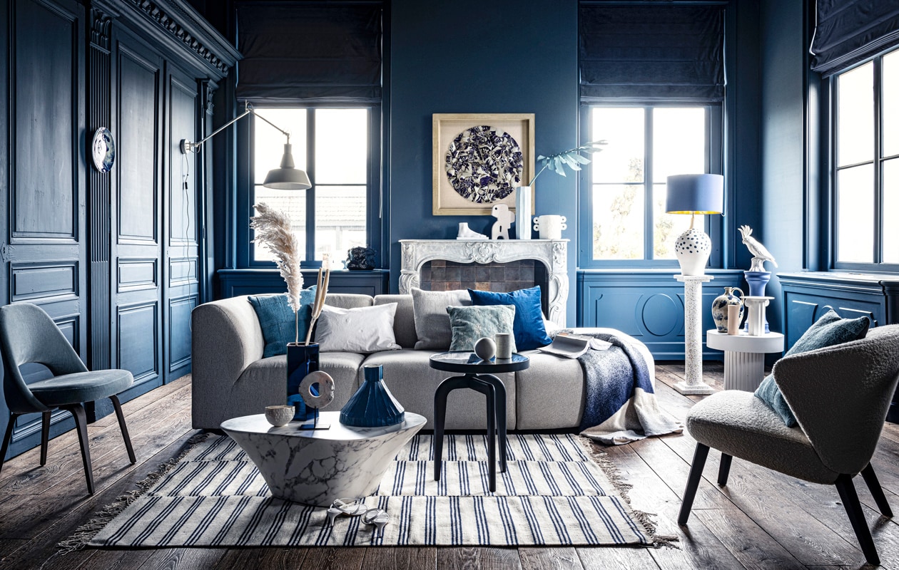 Voet op schouw € 59,95, sierobject op schouw € 58,95, pilaar € 239,-, wit bijzettafeltje € 269,-, witte vaas € 38,35, schilderij prijs op aanvraag (hkliving.nl). Velours stoel € 1200,- (edha-interieur.nl). Kleed € 199,- (zarahome.com). Marmeren salontafel € 587,50, blauwe tak € 57,- (polspotten.nl). Blauwe salontafel Schönbuch € 719,-, plaid Mae Engelgeer € 440,-, wit kussen Mrs.me € 99,- (homestede.nl). Blauw kussen € 49,-, ecru kussen € 49,-, blauw kussen op stoel € 49,- (couleurlocale.eu). Wandlamp It’s about RoMi Chicago € 355,-, kussen Sarona vintage blue 45×45 cm € 35,- (polspotten.nl). Velvet sierkussen 55×55 cm € 74,-, donkerblauwe vaas met tak (klevering.nl), zeshoekige vaas 32 cm hoog € 38,99,-, cockatoo decoratie € 53,- (polspotten.nl), bank Jax hkliving.nl, element vanaf € 499,- (vtwonen.nl). Blauwe vaas, smal toelopend € 469,-, cirkelvormig sierobject € 129,-, wit bankje op tafel, prijs op aanvraag, lichtblauwe vaas 46 cm hoog € 239,-, marmeren pot op blauwe salontafel € 45,-, opengeslagen boek € 40,- (badenbaden.nl). Stoel rechts € 1898,-, sierbal op blauwe tafel, set van 3 € 99,-, houten siervorm op bijzettafel, set van 3 € 99,- (covanderhorst.nl). Schoenen € 34,99 (hm.com). Lampenvoet met stippen € 798,-, gordijnstof 295 cm breed, per meter €103,- (wva.nl). Blauw gevlekte vaas op bijzettafel € 235,95, blauwe kleine pilaar € 66,55, blauwe lampenkap € 332,75, wandbord per twee, € 235,95, marmeren schouw Lodewijk XIV, € 15.125,-, 18e eeuwse houten vloer per m2, € 168,19 (pietjonker.nl). Witte serax vaas op schouw € 40,85 (loods5.nl). Overig privébezit.