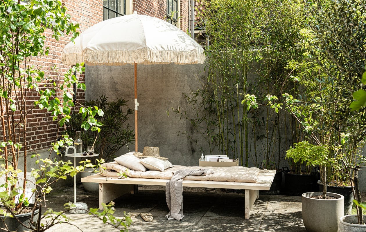 Parasol Dunes € 274,95 (sundaysupply.co). Matraskussen € 69,99, linnen kussens vanaf € 22,99 (zarahome.com). Strohoed € 35,-, zonnebril € 15,-, gevlochten slippers € 69,- (stories.com). Badlaken € 14,99, glazen € 14,99 (hm.com). Bijzettafel Bowler van Hay € 215,-, metalen box van Ferm Living in kleur Cashmere € 65,-, geribbeld glas van Ferm Living, per 4 € 39,- (vtwonen.nl).