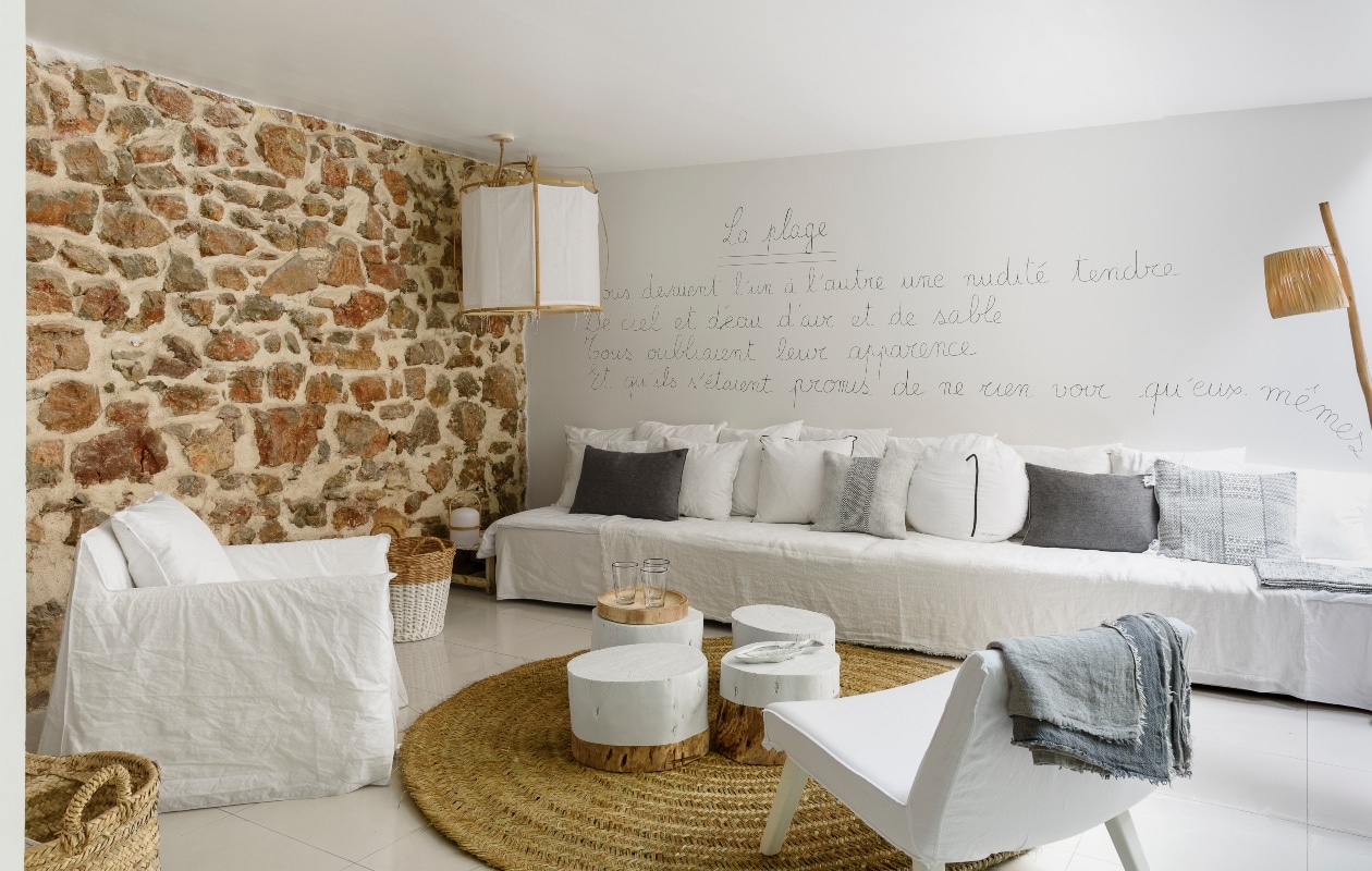 Patricia schreef zelf het gedicht La Plage van Paul Éluard op de muur. De lange bank is op maat gemaakt. Hanglamp Serax, vloerkleed Le Nouveau Décoration, de salontafeltjes zijn handgemaakt
