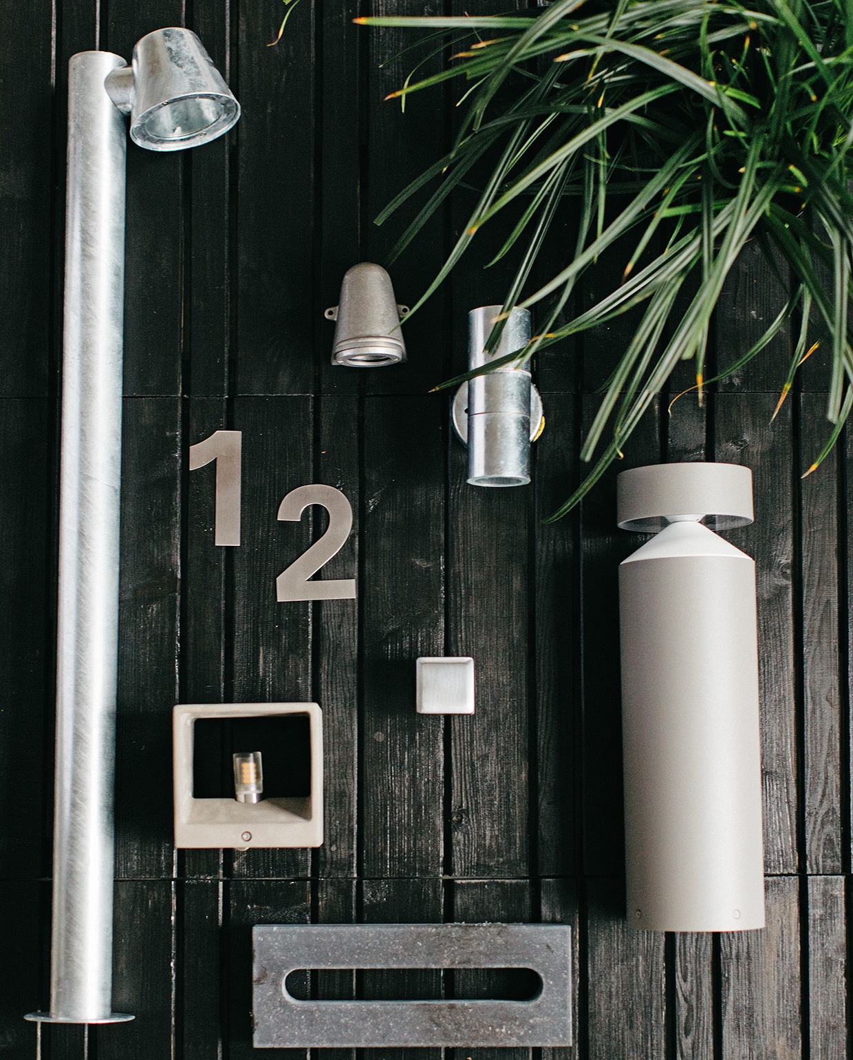 Zwart gebeitste houten vlonders (praxis.nl). Beits van Cetabever (karwei.nl). Rvs buitenbeslag cijfers Jazz, voordeurknop Qbe mat chroom, brievensleuf hardsteen (hardbrass.nl). Gegalvaniseerde staande buitenlamp Konstsmide Trieste, wandlampje Offshore van KS verlichting, gegalvaniseerde up&amp;down spot Konstsmide (fonq.nl). Kubus wandlampje van beton (rietveldlicht.nl). Staande buitenlamp van Eglo (intratuin.nl).