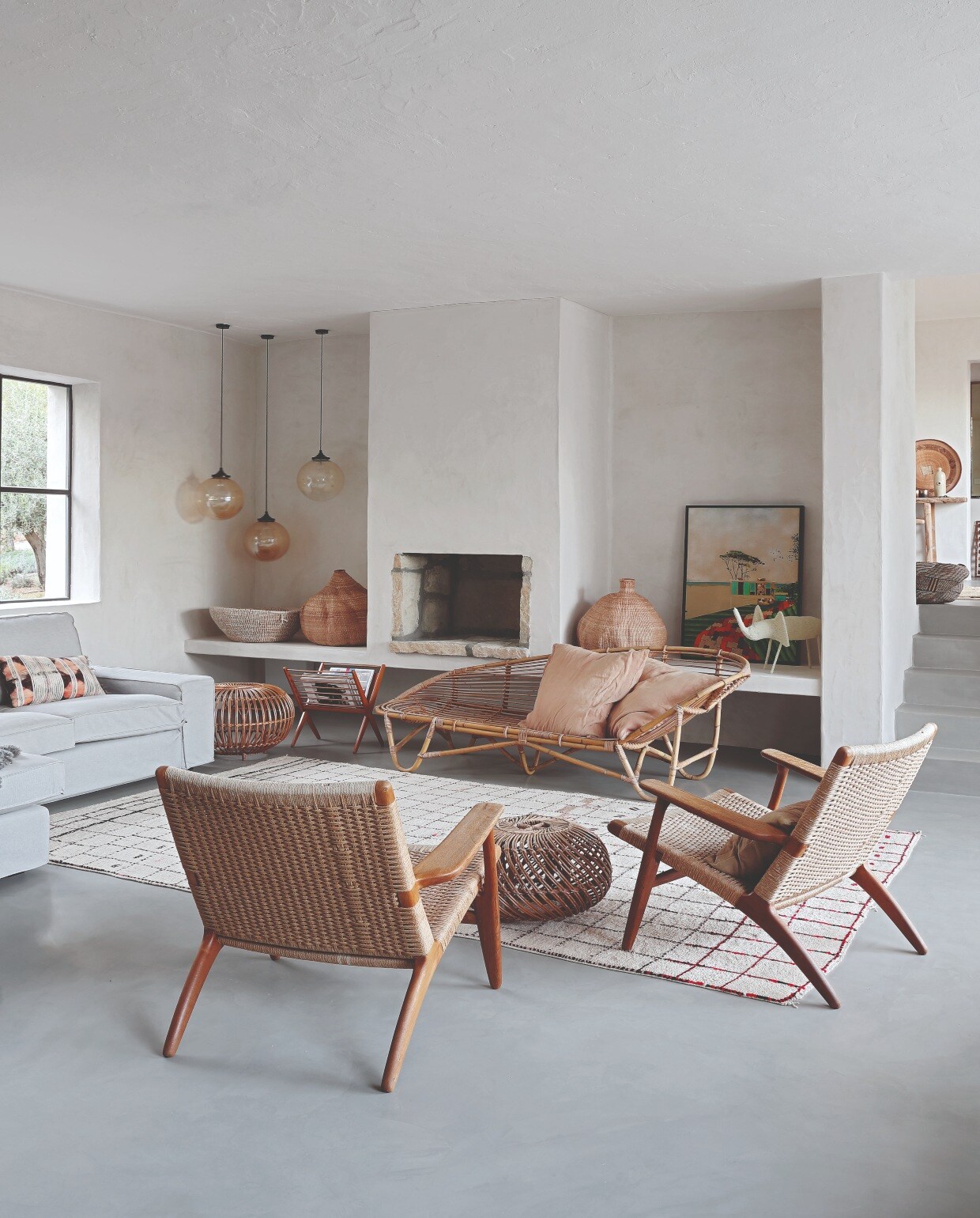 Hanglampen Retrouvius, Hans J. Wegner stoelen van Mid Century Antiques, beide in Londen. Rotan bank Homeplace, Berber vloerkleed uit Marokko. Grijze bank Ikea, schapenvachten The Organic Sheep. Schilderij van de Australische kunstenaar William Mackinnon