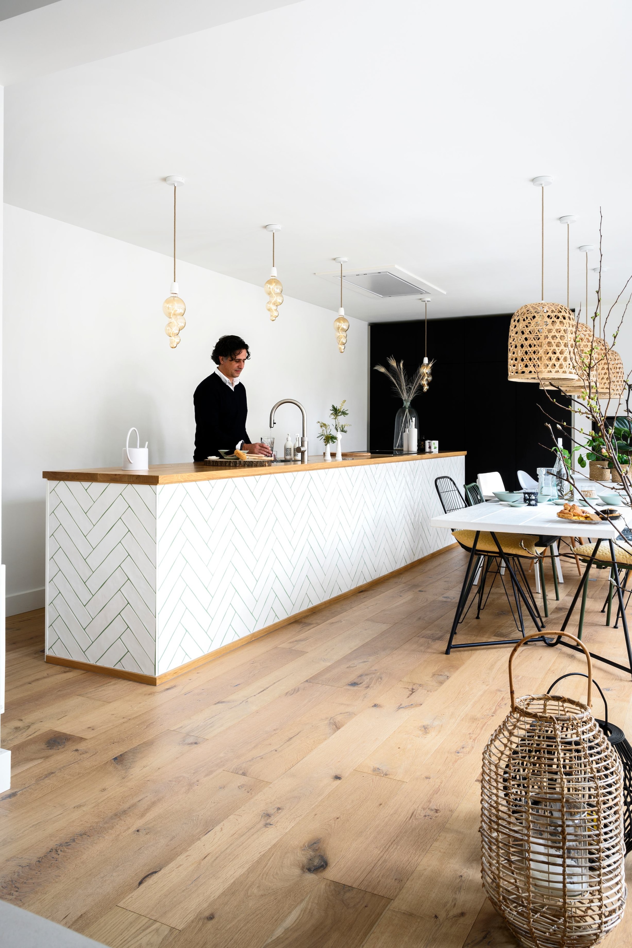 Keuken, tafel en kasten maatwerk van Meubelmakerij M’n Broer en Lacombe Interieurbouw. Tegels designtegels.nl, eikenhouten vloer De Vloeren Kenner, kleine lampen Calex XXL Alicante, grote lampen Woonexpress. Glazen en karaf Pols Potten. Witte stoelen House Doctor, groene stoel Gamma, overige Marktplaats. Manden Kwantum, haard Pook Haarden.