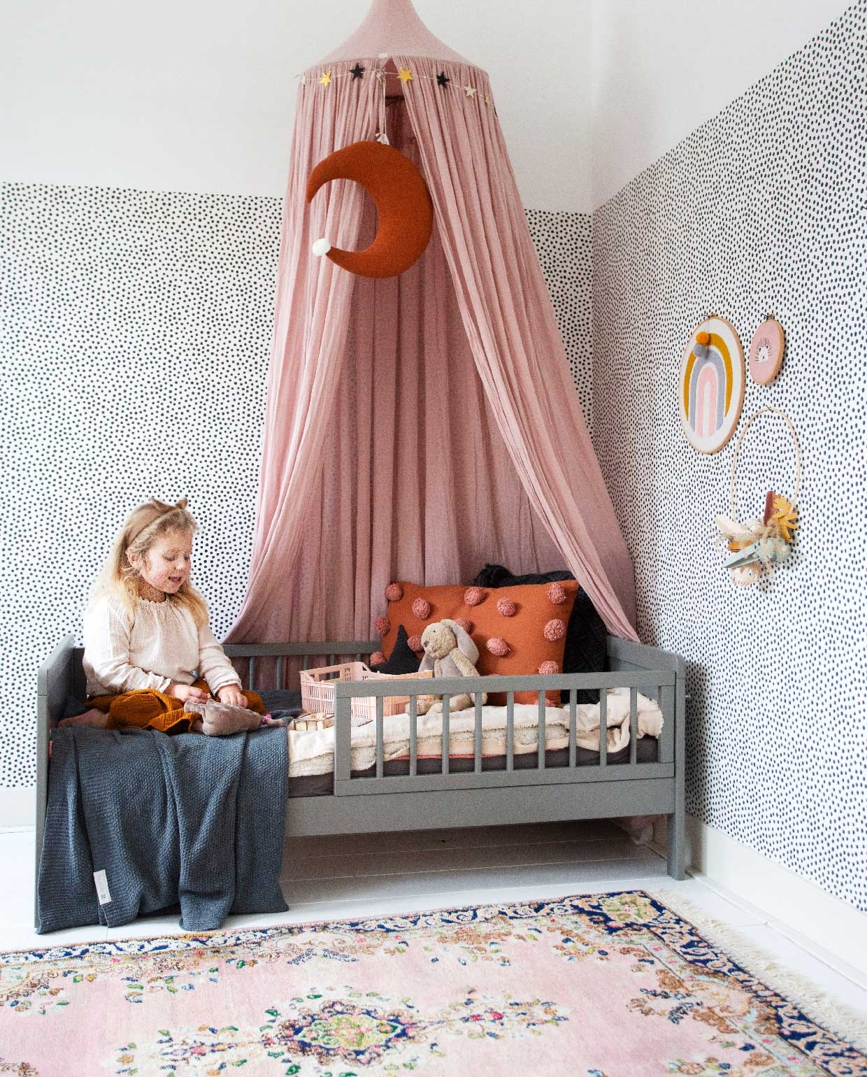 Behang en oranje kussen Kwantum, bed Petit Amelie, klamboe Nummero 74 via Archive Store, maan via Noa May, jeans plaid By Mölle, vloerkleed van Susanne’s oma.