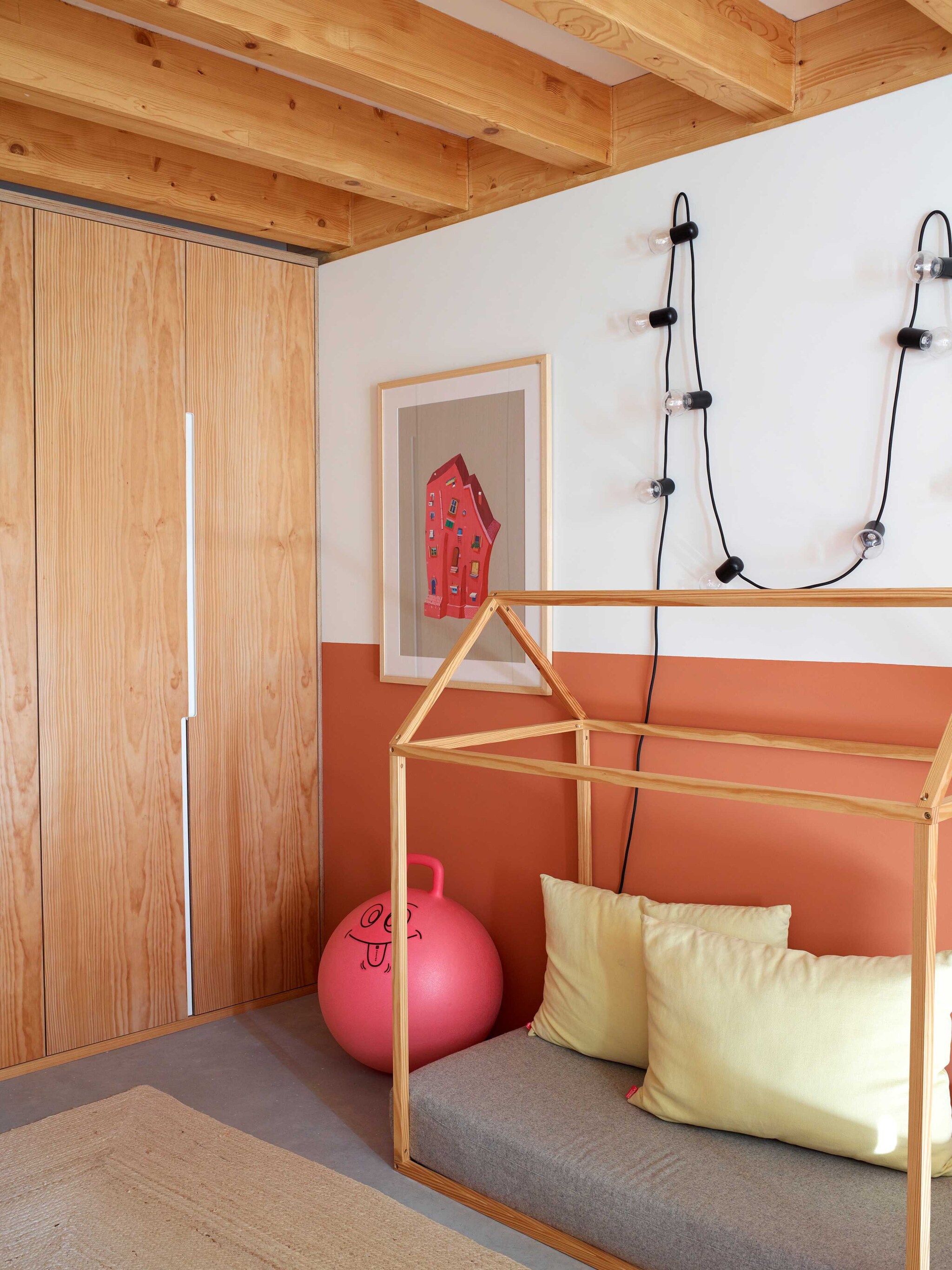 Het houten daybed in de vorm van een huis op de kamer van Maria do Carmo is een ontwerp van Marta. Kussens Moopi Design. Kunstwerk Ana Aragão. Kasten ontworpen door César. Soortgelijk lichtsnoer Seletti.