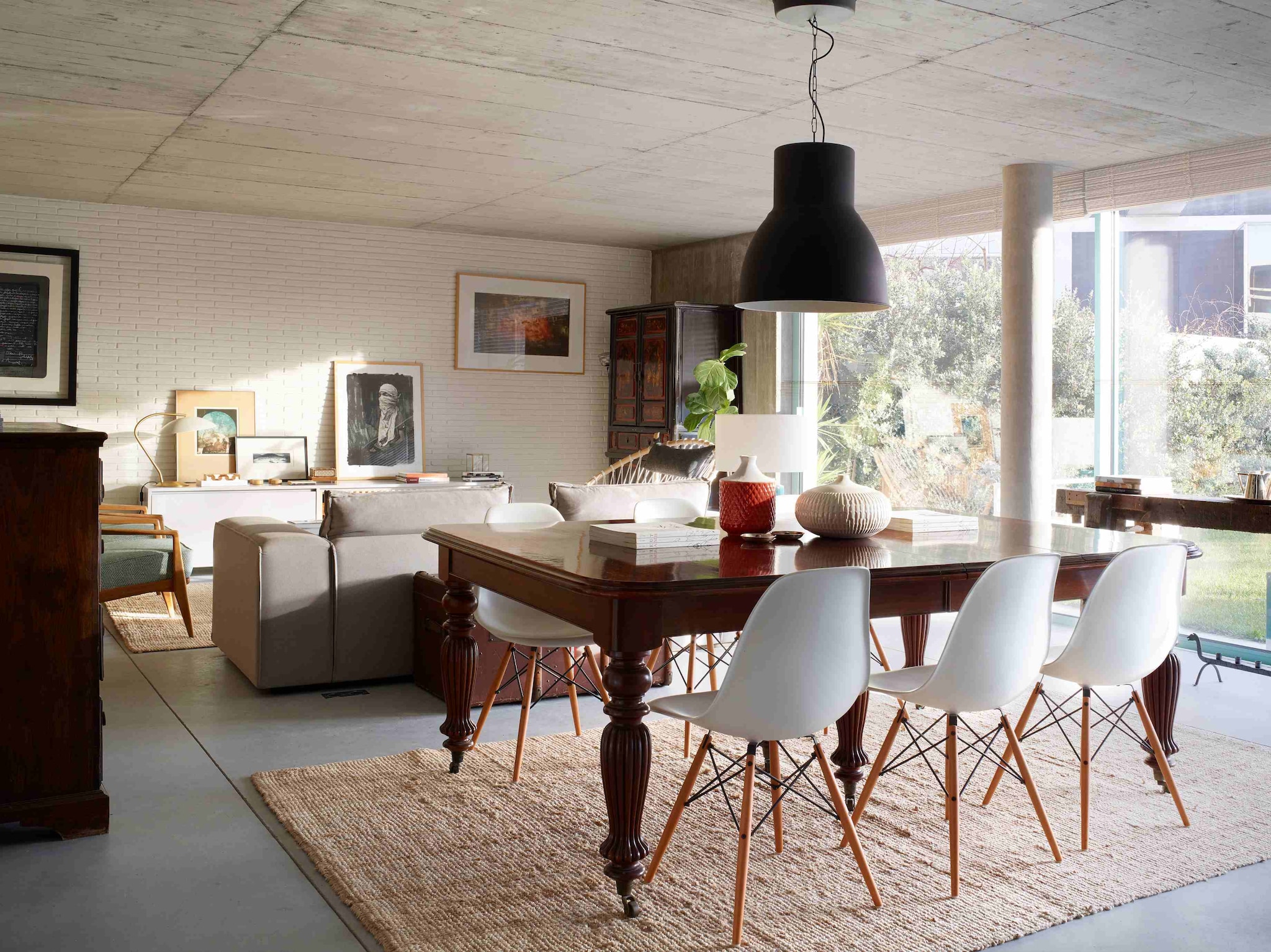 Eettafel en hoge kast antiek. Stoelen DSW van Eames (Vitra). Vazen op tafel Zara Home. Hanglamp en kleed Ikea. Bank en lage kast tegen de muur ontworpen door Marta. De kunstwerken aan de muur en links op de lage kast zijn gemaakt door Marta’s oom Bartolomeu Cid dos Santos. Groot zwart-wit kunstwerk rechts op lage kast Sainer. Blauwe fauteuils vintage.