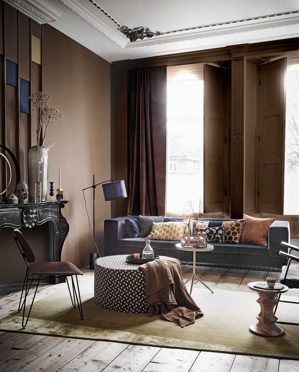 Op de muur, verf per liter: bruine verf Komeet, blauwe verf Ink Blue van Pure &amp; Original, gele verf Luxe S2060-Y10R van Histor (deruamsterdam.nl). Alle stoffen per meter, tenzij anders vermeld: gordijnstof bruin Colour Box velvet f111/11045 (cole-and-son.com). Lampenkap links van de bank van blauw velours-, kussen met fijn dessin van Nobilis-stof, grafische kussens van Designers Guild-stof, kussen helemaal rechts, messing lampvoet (wva.nl). De stof van de poef is Opio van Manuel Canovas (barbaraemmy.com). Bank in blauw velours Loods 5, goudkleurige bijzettafel (loods5.nl). Hoge vaas op de schoorsteenmantel (homestede.nl). Ringvormig object, blauw met amberkleurige kandelaar, blauwe glazen vaas en bruine vaas prijs op aanvraag, bruine glazen pot op goudkleurige tafel, mok op de houten tafel van HK Living, oranje glas op dienblad (loods5.nl). Bruine plaid, zwart dienblad (hm.com). Stoel met leren bekleding (brechtmurreatelier.nl). Vloerkleed, houten kruk van Vitra (covanderhorst.nl). Overige privébezit.