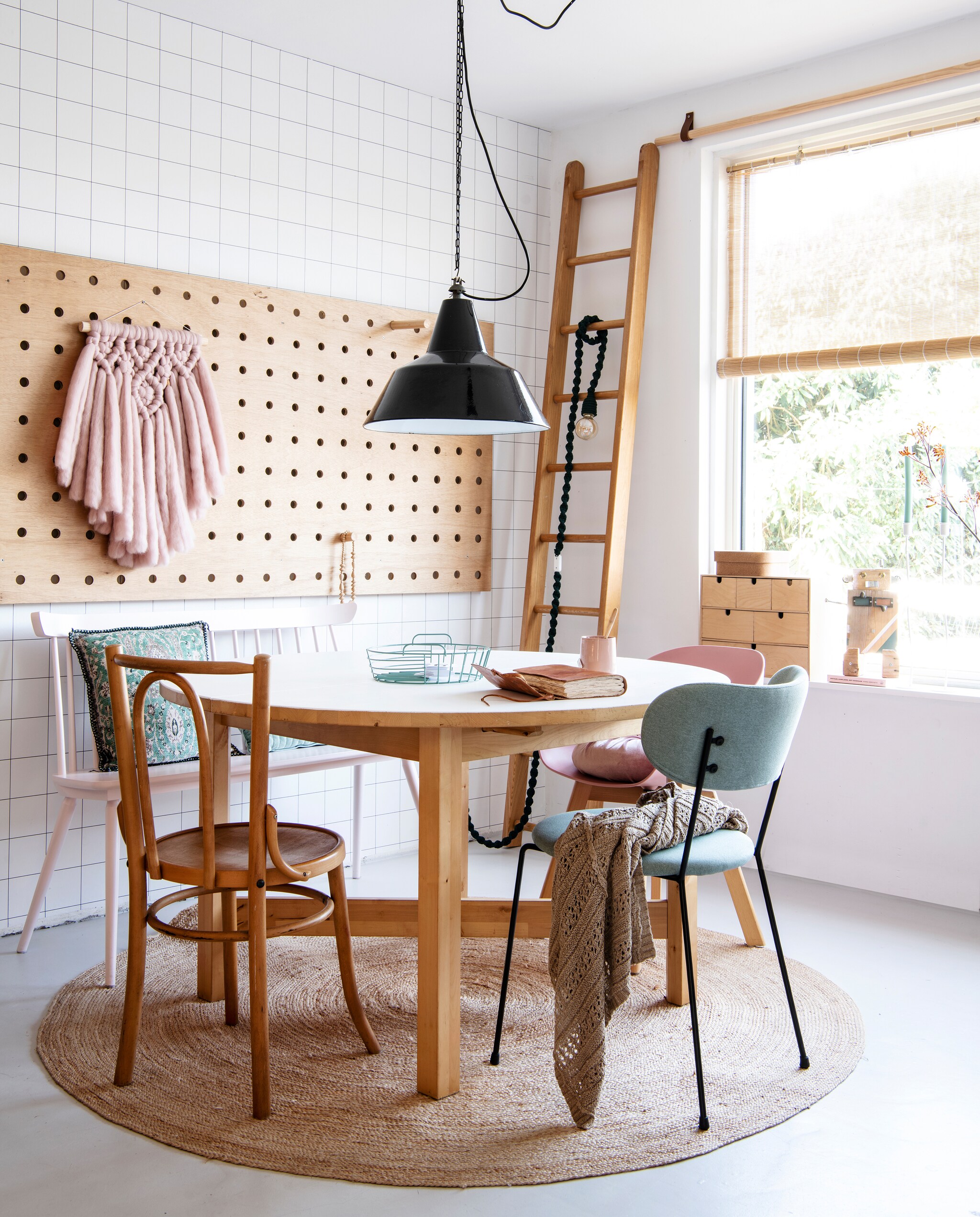 Ronde tafel van Ikea. De zwarte hanglamp, houten stoel en oude ladder vond Lotte op een vlooienmarkt. Het roze bankje is vintage. Kussen van By Boo. Roze