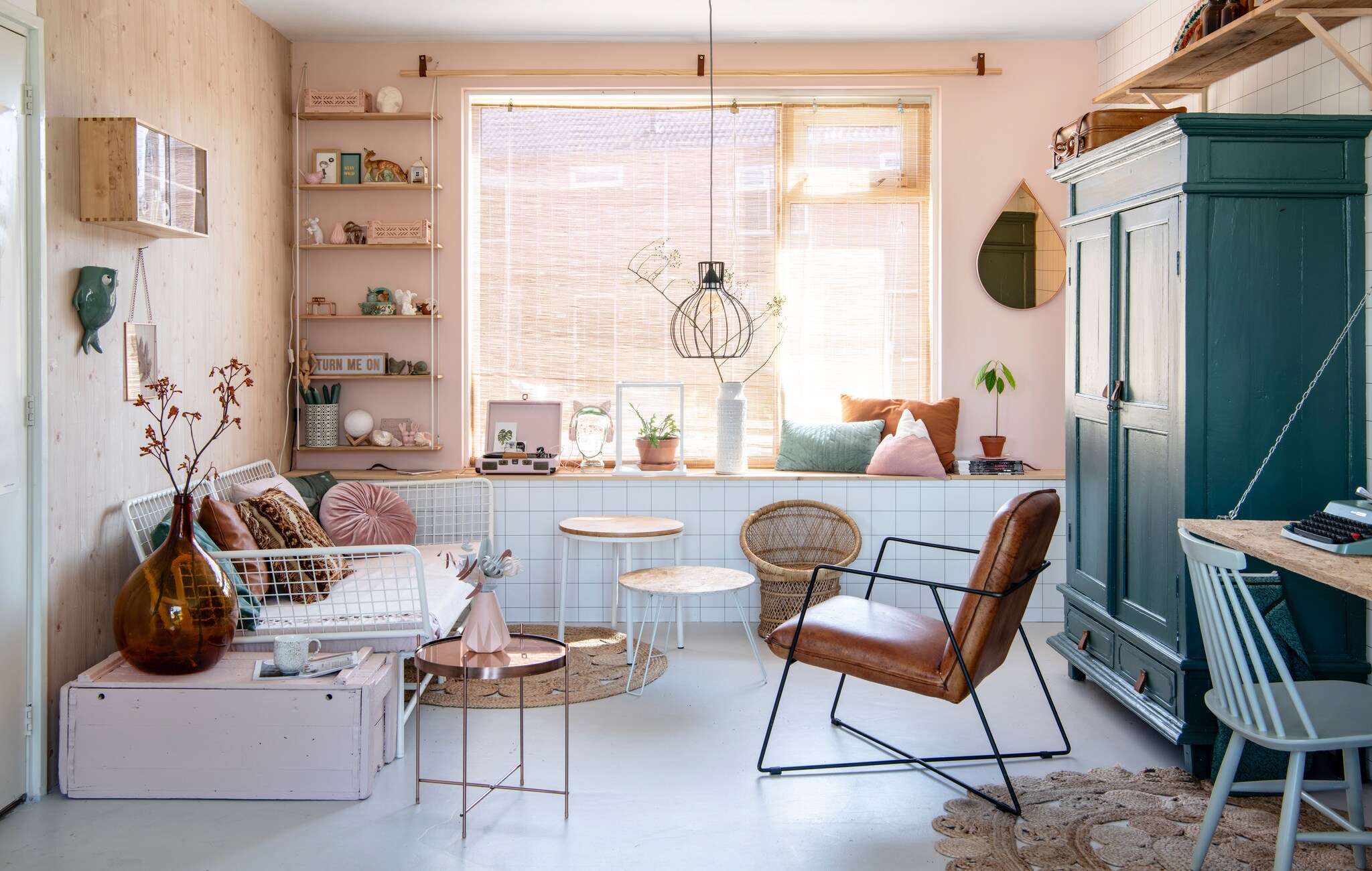 Bank van Ikea. Behang met houtmotief van Karwei. Kussens (van links naar rechts): Sissy-Boy, tweedehands, Hema, Hornbach. Koperen tafel van Zuiver. Hoge koffietafel van Hema. Lage koffie-tafel en wandrek van Søstrene Grene. Kleed van Kwantum. Leren stoel van Plofshop. Roze platen- speler van Crosley. Lamp en kistje met camera’s van de kringloop. Roze vaas en groene vis Mica. De grote bruine vaas kreeg Lotte van haar moeder. Lijstje van Sissy-Boy.