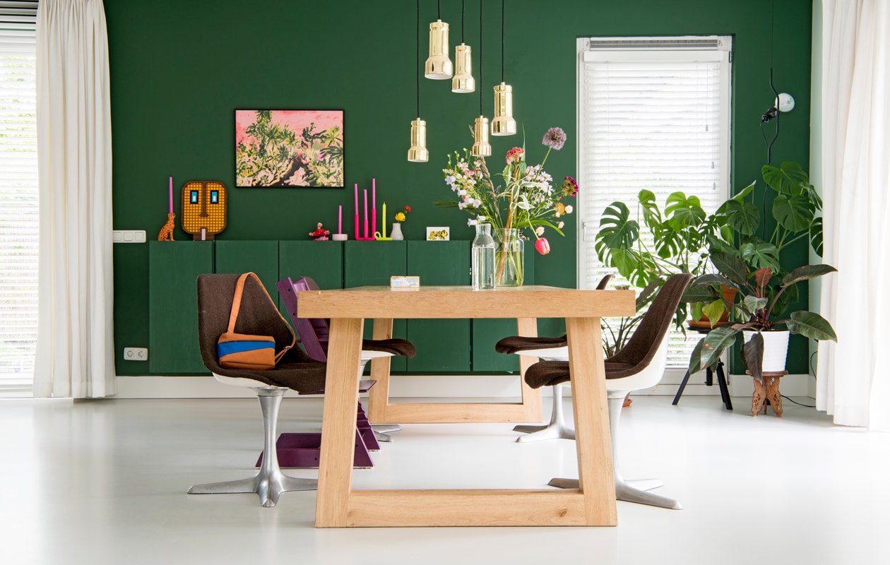 Groen geschilderde Ivar kasten Ikea. Luipaardkandelaar &amp;Klevering. Wit-oranje masker umasku.com. Roze print French Toast Studio. Roze kandelaar Ikea, gele Ontwerpduo. Hanglampen Frandsen. Tafel op maat eikentafels.nl. Stoelen vintage. Plantentafel van Linda’s grootouders. Staande lamp Floss Parentesi. Muurverf kleur Zinnia van Histor.