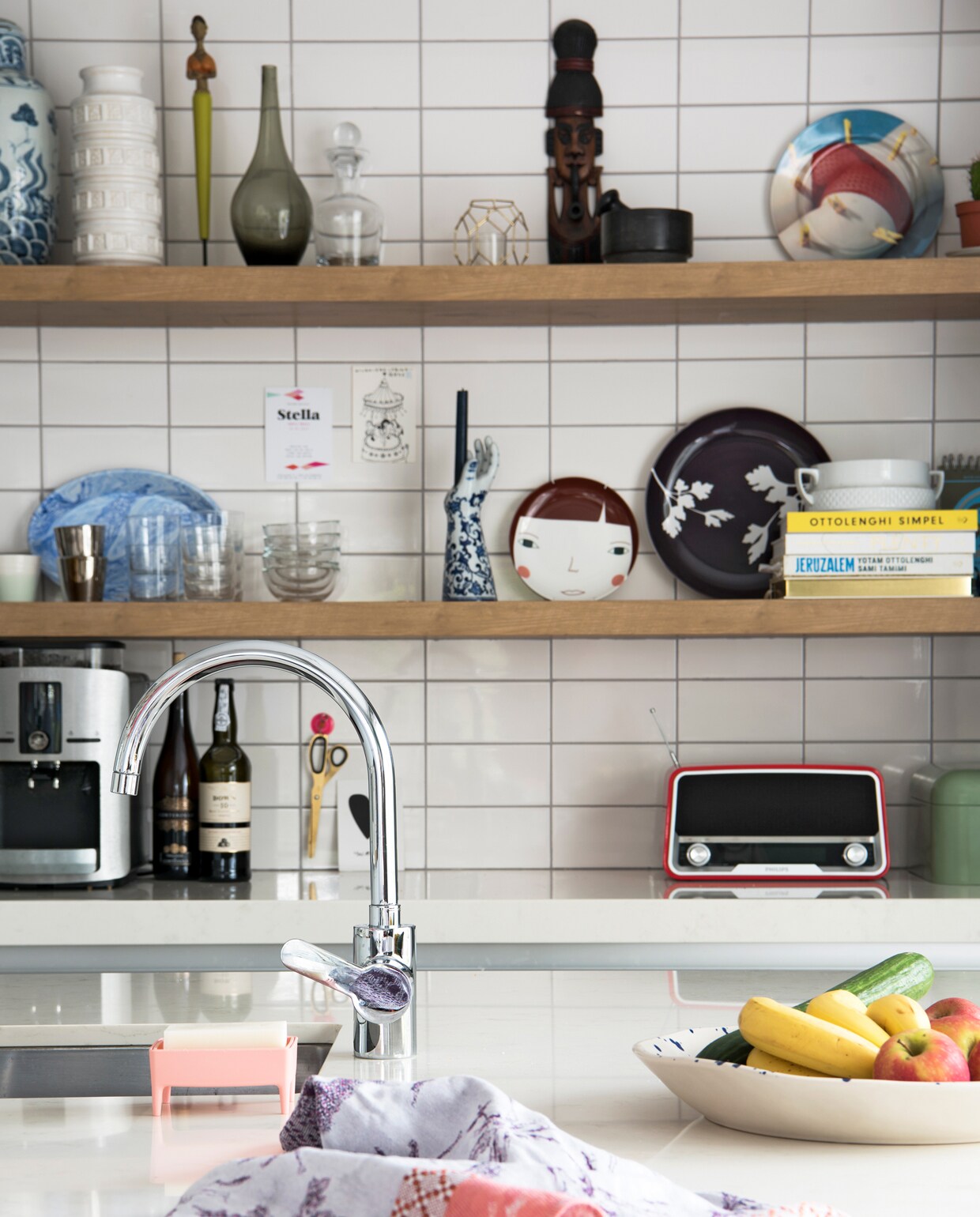 In de keuken staat een collectie potjes, glaswerk en borden uitgestald op Bruynzeel planken. Met de klok mee: vaasjes kringloop, beeldje van Linda’s oma, grijze glazen vaas Ikea, masker uit Thailand, bord Springs Laundry van Seletti mudinmay.com, zwart bordje Ikea, bord met gezichtje Donna Wilson, blauwwitte Hands Up Candleholder van Pols Potten, blauw bord van Hay.