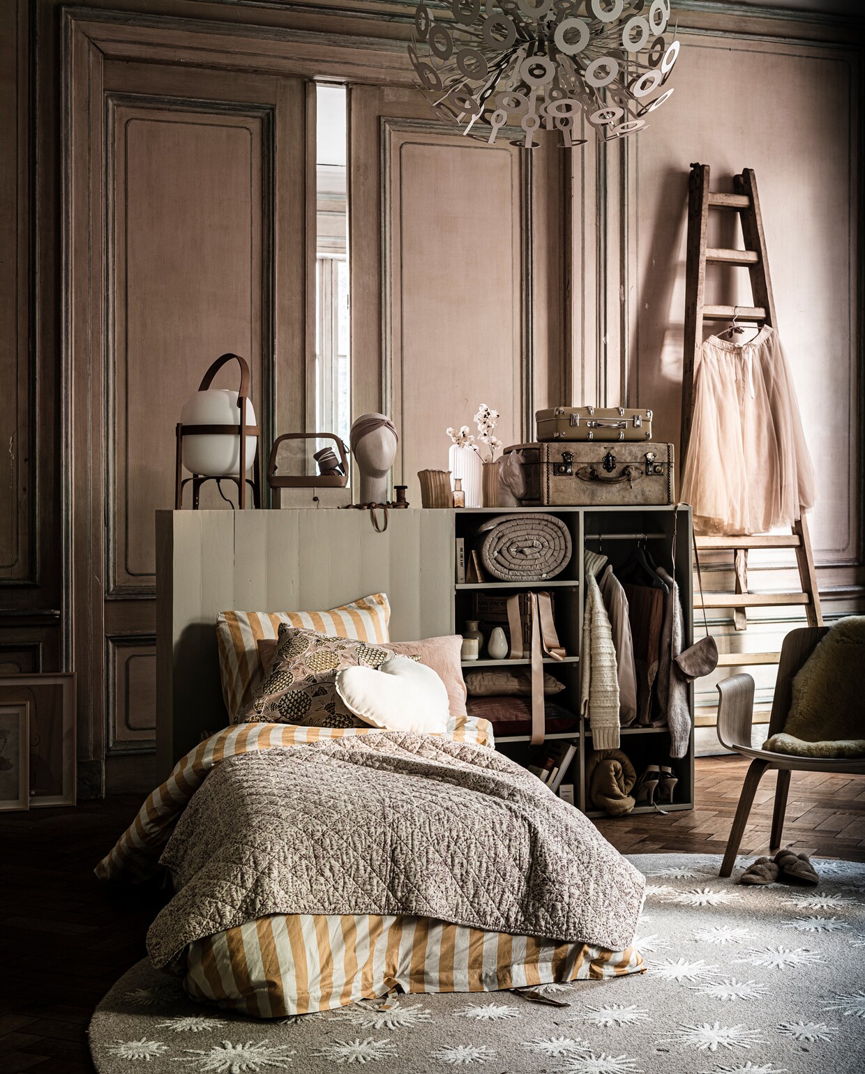 Bed met bedwand/kast aan de achterkant als kast te gebruiken, prijs op aanvraag (com-anders.nl). Doosje met bruine knoop op kast, sokken in etui, trui links in kast, blouse in kast, vest rechts in kast, tasje Philomijn aan kast (sukha.nl). Doorzichtig etui, kop met haarband, paardenkopvaasje, hakken in kast (hm.com). Klosje met lint (tinekhome.com). Vaasje met imperfecte vorm van Floris Wubben, staande lamp Cesta Santa &amp; Cole (frozenfountain.nl). Oranje flesvaasje, plaid op het bed met roze bloemenmotief (weldaad.com). Lichte vaas achter op kast, kussen in kast met leren stiksels (loods5.nl). Bovenste koffer, 40 cm, opgerolde bed bumper, kussen hart maat M, mosterdkleurige plaid onder in kast, kussen op bed van zalmkleurig linnen, schapenvacht op stoel (archive-store.nl). Oude koffer onderop stapel, ladder tegen muur (wildschut-antiques.com). Zalmkleurige rok aan ladder (pauw.com). Houten palmfauteuil van Bolia, 73×72,2×66,2 cm (hxbxd) (vtwonen.nl). Sloffen op grond, zalmkleurige pyjama in kast (zarahome.com). Vloerkleed met bloemenprint, 280 cm (roche-bobois.com). Dekbedovertrek met streep (hay-amsterdam.com). Kussen met motief op bed (bungalow.dk). Grijs boek boven in kast, rond beige vaasje met tuitje op de tweede plank van boven achterin (maisonnl.com). Gele beker met witte rand, peervormig wit vaasje, roze kratjes met lint erin, paperclips (letoile.store). Donkerroze met bruin kussen (homestede.nl). Overig privébezit.