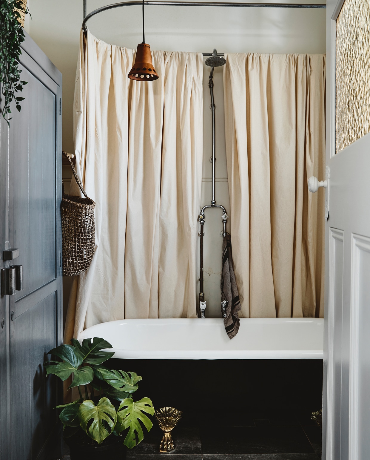 Het antieke bad op messing pootjes stond al in het huis. Kast en lamp van HK Living. De plant is een Monstera deliciosa.