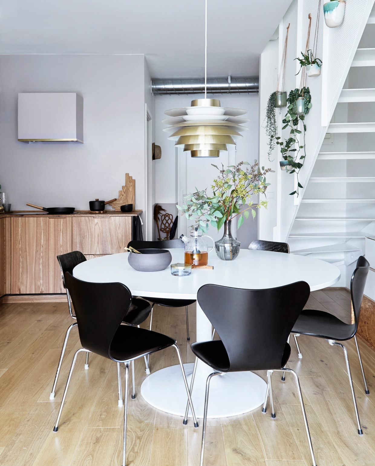 De eettafel is een ontwerp van Ejvind A. Johansson, hanglamp Verona van Svend Middelboe gekocht bij Lysfabrikken. Stoelen Fritz Hansen. Lamp Lysfabrikken. Theepot Menu, onderzetter Skagerak, kom Ro Collection, glazen potje Aytm, vaas Ikea.