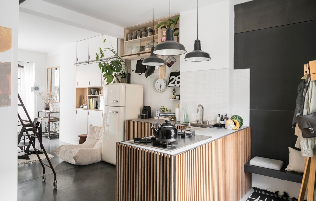 Naast de opnieuw gestoffeerde Togo fauteuil van Ligne Roset staat een kruk van Wøti, Williams eigen label. Koelkast Smeg, vintage klok van Pragotron gekocht bij Blom &amp; Blom. De keuken die William maakte is een hit op Pinterest. Het werkblad is van beton, de kastdeuren van zwarte mdf met slaglatten in meranti-hout. Lampen van een brocantemarkt in Frankrijk.