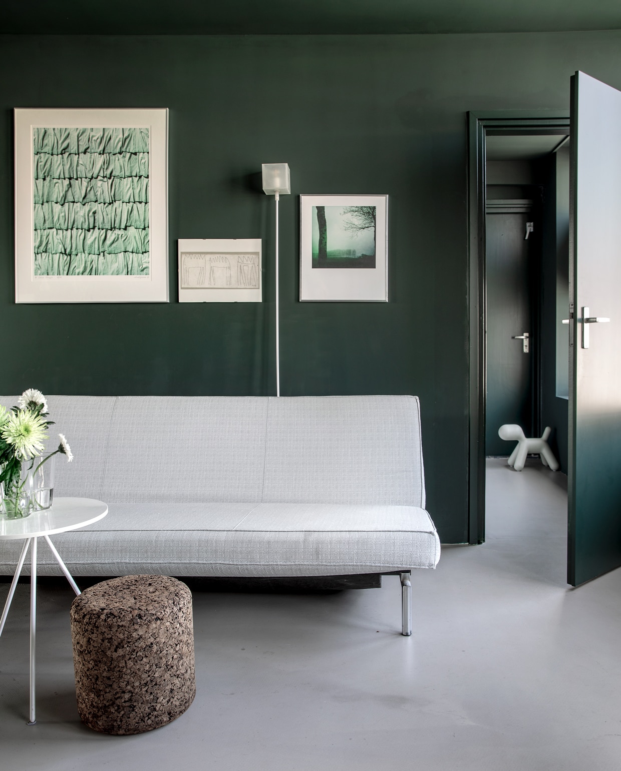 Egalisatievloer Forbo Eurocol. Zeefdruk Klaas Gubbels via Marktplaats. Kunstwerk van Aad Schram via Art Olive. Vloerlamp Lazy van Chris Slutter voor Goods (smukdesign.nl). Foto van Anya van de Wetering. Hond Puppy van Magis via musthaves.nl. Rond tafeltje Bijenkorf.