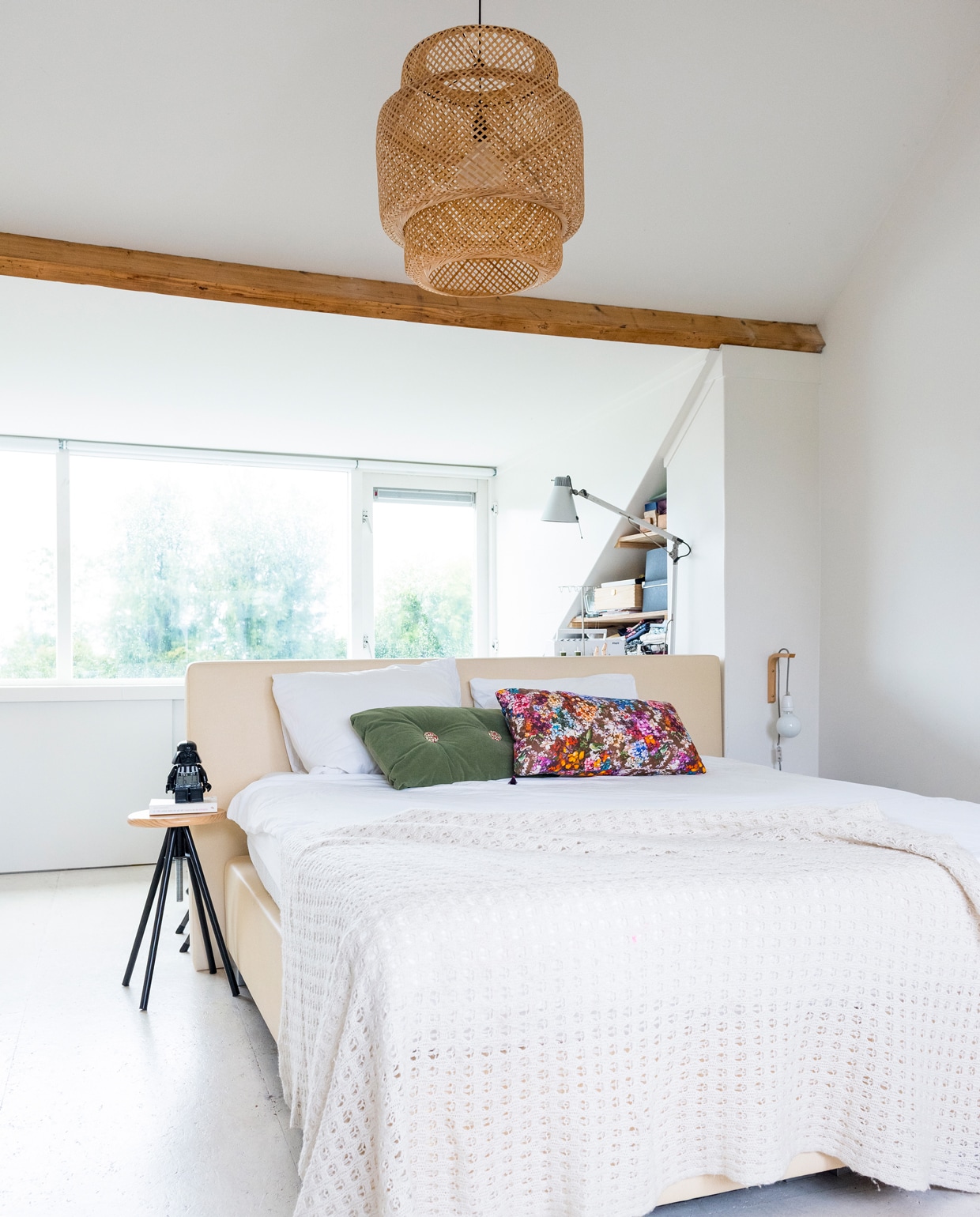 In de slaapkamer van de ouders op de bovenste verdieping zat voorheen een vliering. Deze is opengebroken voor meer ruimtelijkheid, de balken zijn daarbij in het zicht gelaten voor de sfeer. Krukje van de Action, daarop een Star Wars-wekker van bol.com, hanglamp van Ikea, bed van lokale beddenwinkel in Rotterdam, sprei onbekend, wandlampje zelfgemaakt met spullen van snoerboer en een plankendrager, metalen lamp van Erco, beddengoed Essenza.