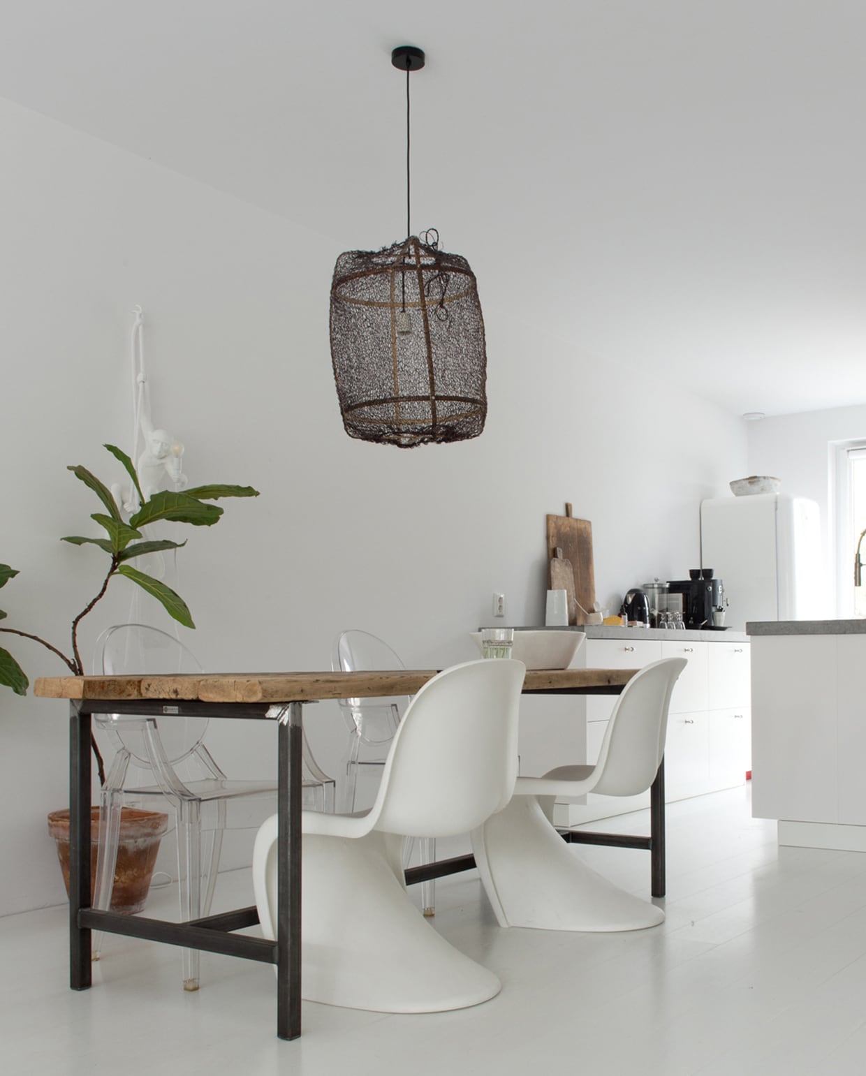 De witte Verner Panton stoelen en de Ghost Chairs van Kartell vormen een mooi contrast met de ruwe houten eettafel van Barn9 Woodconcepts. Lamp Ay Illuminate van loftloft.nl. Broodplanken uit Frankrijk. Vloer van Strongfloor. De keuken ontwierp Dennis zelf, de lades zijn van Ikea.