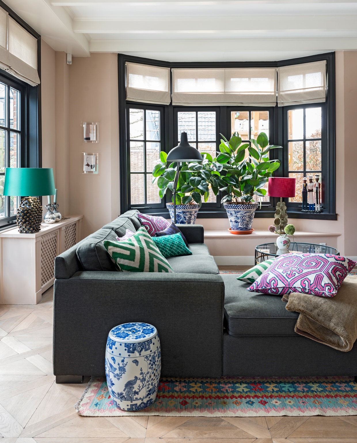 De zetel en staande lamp komen uit een woonwinkel die niet meer bestaat. Lamp met roze kap Eveline Interieur. Kussens van Eveline Interieur, Elitis en Mariska Meijers. Plaid herkomst onbekend. Kleed groothandel. Chinese pot stond in de kelder van Diederiks ouders. Salontafel Paul Lelieveld. Potje groothandel. De beelden op de vensterbank komen uit Afrika. Plantenpotten uit Spanje, verkrijgbaar bij Studio Sophie. Lijsten aan de muur van HK Living. De zilveren kandelaars waren een cadeau van Sophies ouders. Muurverf Setting Plaster van Farrow &amp; Ball. Vouwgordijnen zaten al in het huis. Kozijnen geschilderd in kleur Ral 9004.