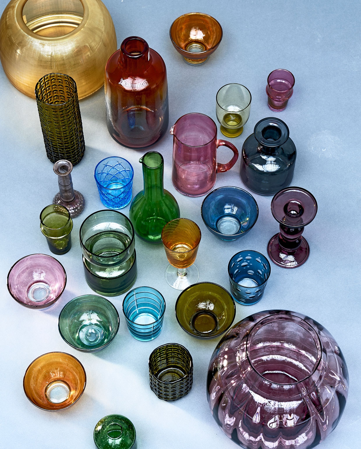 Van boven naar beneden, v.l.n.r.: goudkleurige vaas, rode vaas (polspotten.nl), oranjebruin parelmoeren schaaltje, groene bewerkte vaas (householdhardware.nl). Groenbruin glas op pootje (hkliving.nl). Donkerroze glaasje met ribbel, roze karaf (householdhardware.nl), blauwe apothekersvaas (ikea.com). Mauve kandelaar (weldaad.com), korenblauw glas Flimra met wieberpatroon (ikea.com), groene karaf met smalle hals, blauw parelmoeren schaaltje, groen glaasje met ribbel (householdhardware.nl), groene vaas (hkliving.nl), oranje wijnglas (polspotten.nl), blauw parelmoeren schaaltje (householdhardware.nl), bordeauxrode kandelaar (weldaad.com), lila en groen parelmoeren schaaltje (householdhardware.nl), lichtblauw bewerkt glas (polspotten.nl), donkergroen parelmoeren schaaltje (householdhardware.nl), donkerblauw bewerkt glas (polspotten.nl), oranje parelmoeren schaaltje, laag groen bewerkt vaasje (householdhardware.nl), grote paarse vaas uit de Copier Revisited collectie, hoogte 25 cm (royalleerdamcrystal.nl). Groen rond vaasje (weldaad.com).