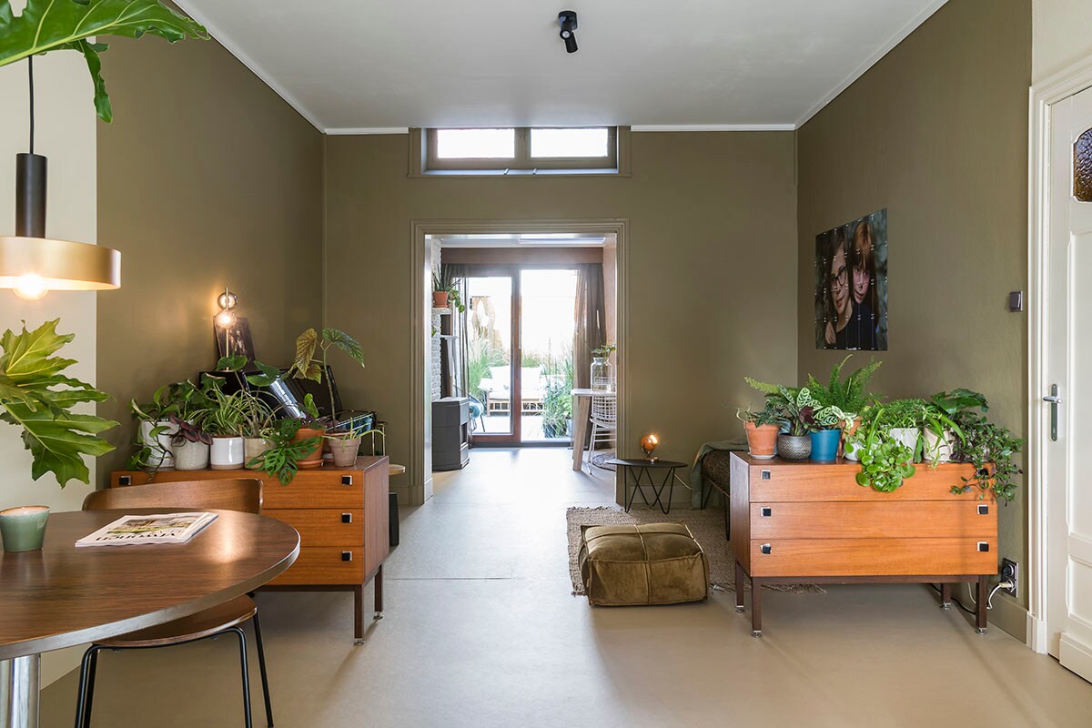 Stoelen (BePureHome), hanglamp boven tafel, tafellamp op piano en zwarte spot (Lucide), poef – honey (BePureHome), tapijt – jute (HKliving), zwarte bijzettafel, oranje tafellamp, eettafel en vintage kasten (privébezit).