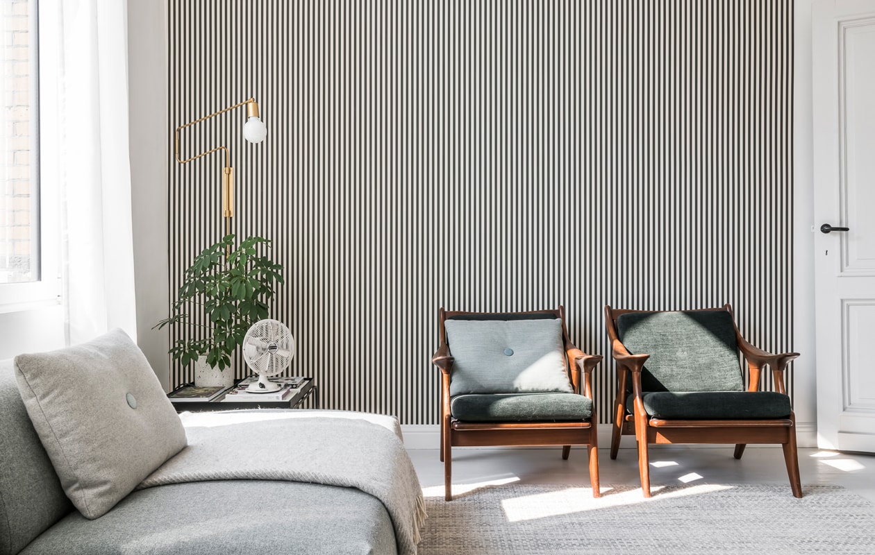 Het streepjesbehang is van Ferm Living, de vintage fauteuils met groene kussens vonden Sofie en Yannick bij Nome Furniture. De goudkleurige leeslamp is van House Doctor.