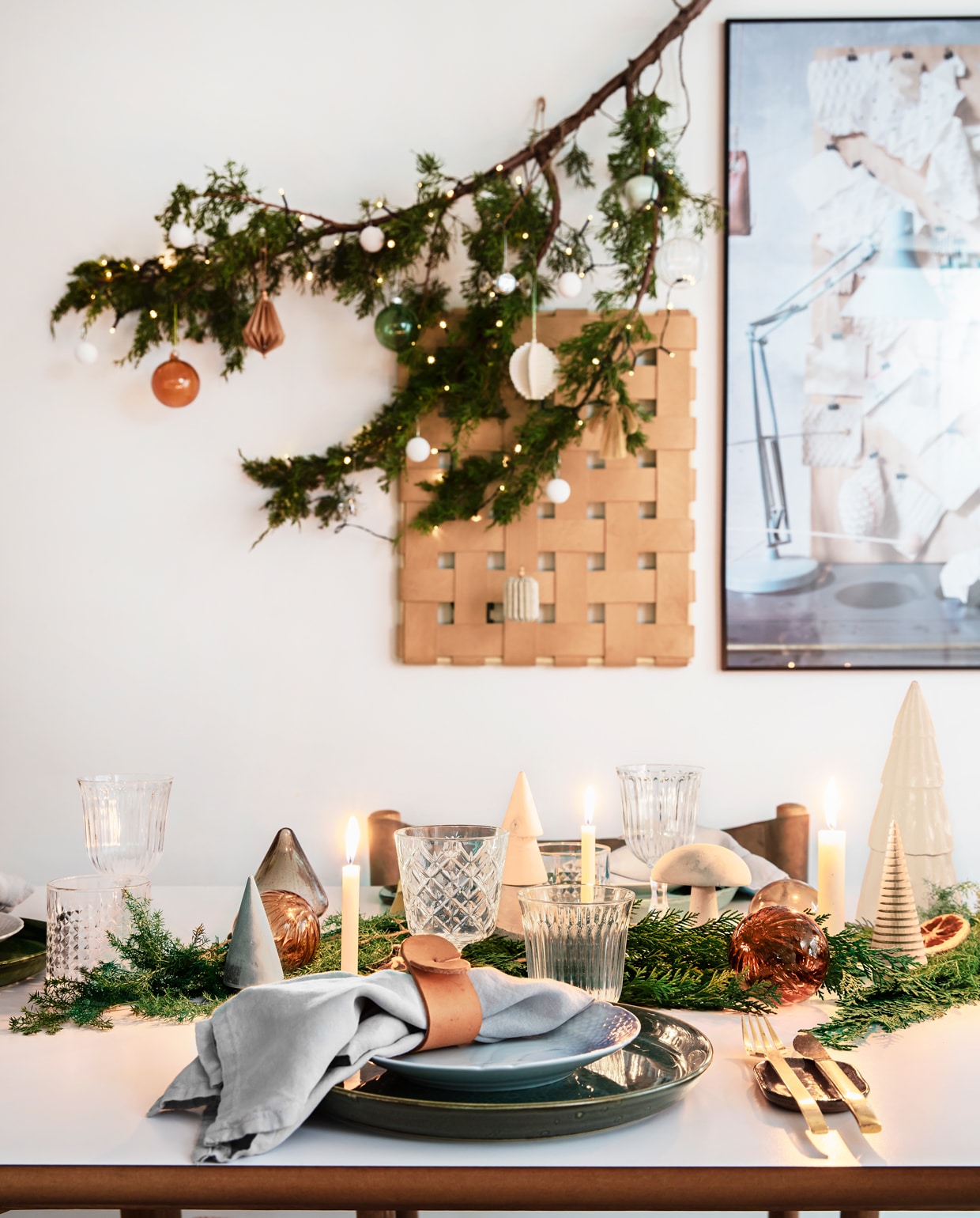 Het groen van de takken, samen met het leer en hout, bepalen de sfeer op de kersttafel. De leren servetringen maakte Rikke zelf.