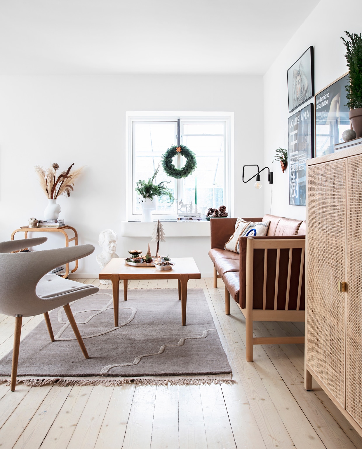 Hout, leer en keramiek spelen een belangrijke rol in huis. Bank van Skovby Furniture, vintage salontafel van Børge Mogensen, fauteuil van Stouby. Kleed van Ferm Living. Op tafel zelfgemaakte kerstkoekjes in kleine glazen, omringd door noten, pijnboomtakjes en kleine en grote kerst- bomen van hout die Rikke zelf maakte.