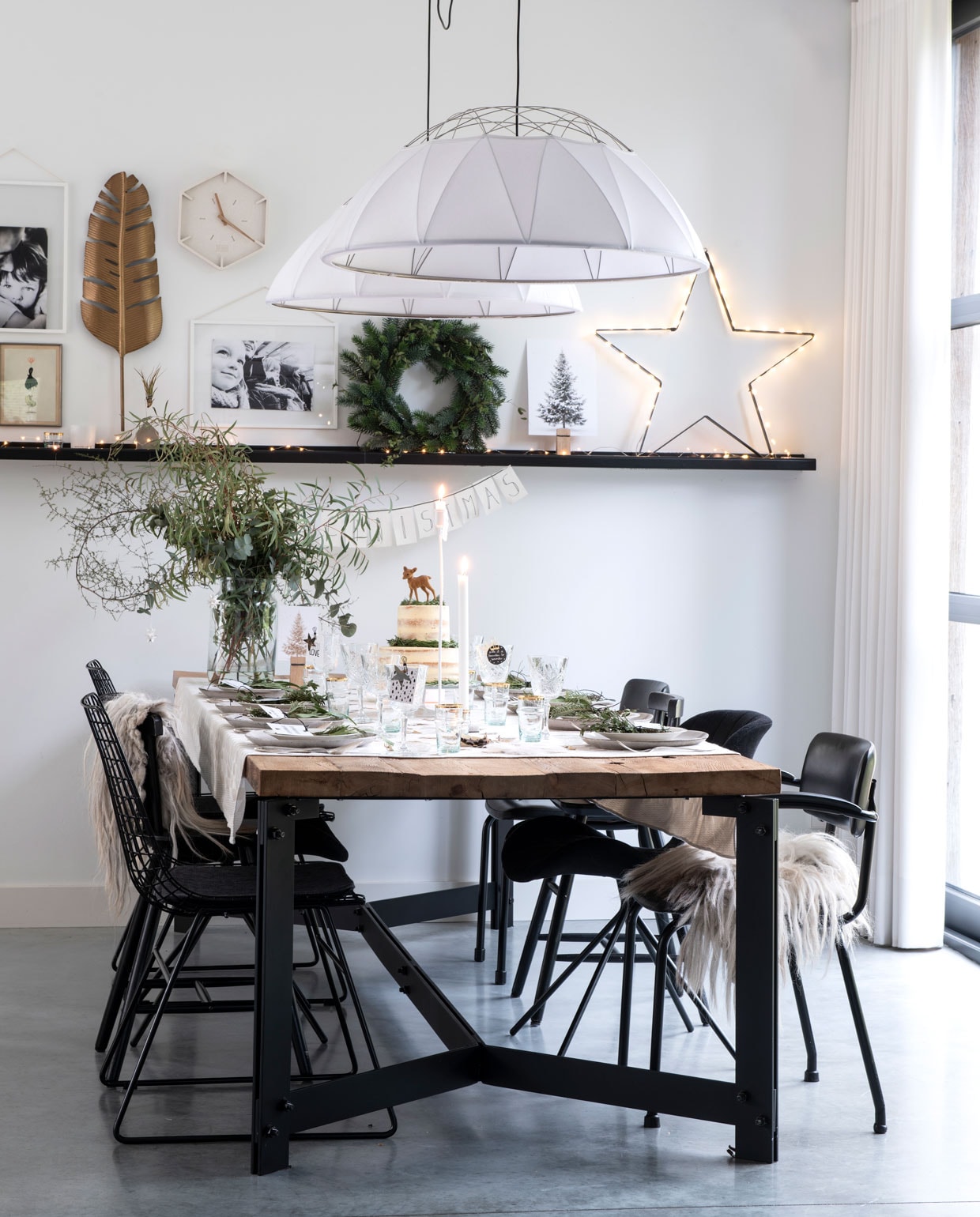 De eettafel is gemaakt door Robuust Maatwerk, van oud schuurhout en staal. Stoelen van Zuiver en HK Living, Ikea (kinderstoel) en een vintage stoel. Hanglampen Glow van Marc de Groot voor Hollands Licht. Veer van Dames van Rusticus Styling, klok van By-Boo, ster van Stoer Metaal. Vachtjes van Vacht van Vilt.