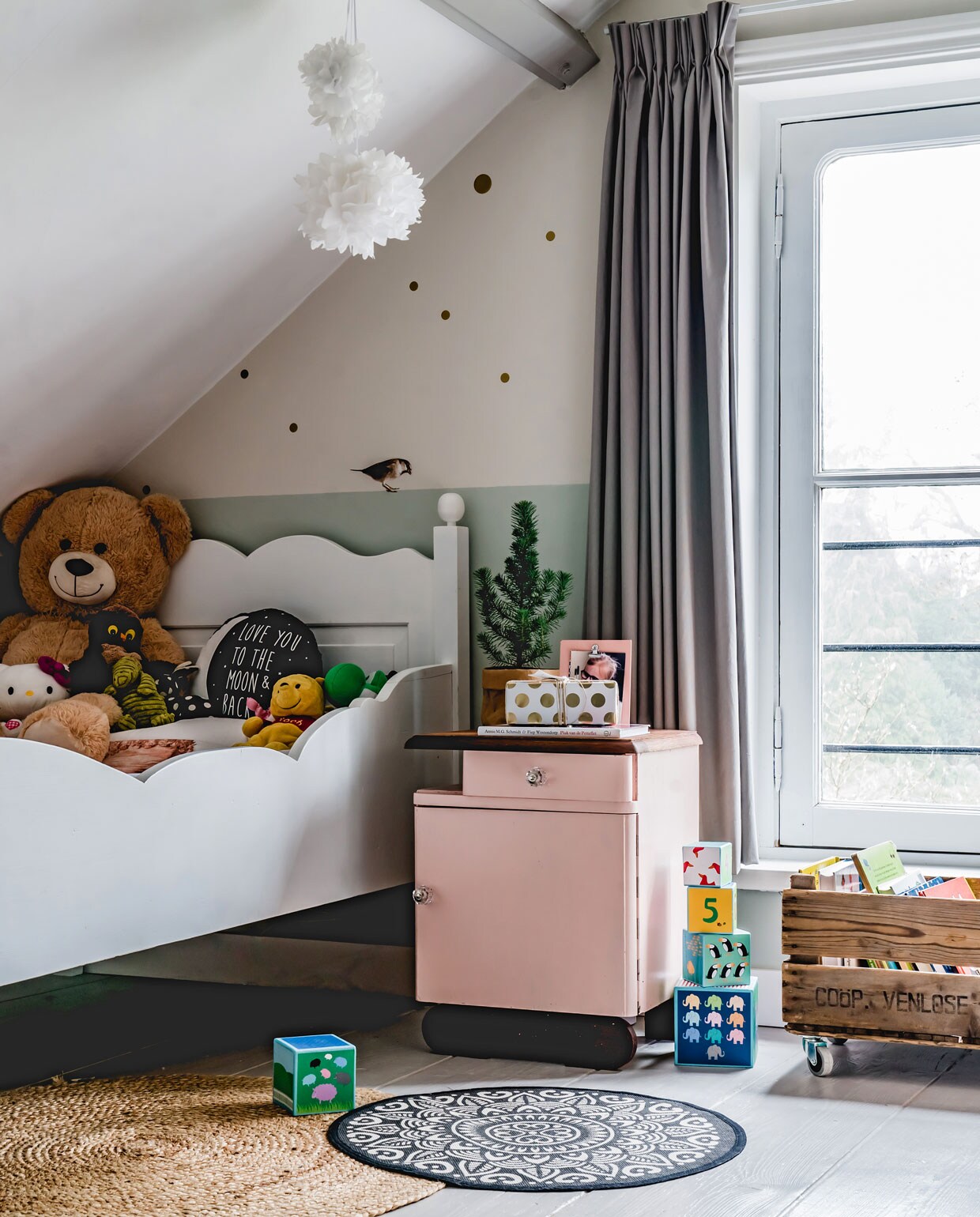 De lichtgrijze balken op de kamer van Soof hebben dezelfde kleur als de vloer, Balanced Breeze van Flexa. Het nachtkastje is gevonden op marktplaats.nl, Marjolein schilderde het roze. Ook het bed vonden ze daar. Vloerkleden Kwantum en Kruidvat, krat op wielen via via uit een oude fabriek, vogel op muur Kek Amsterdam, herkomst lamp onbekend.