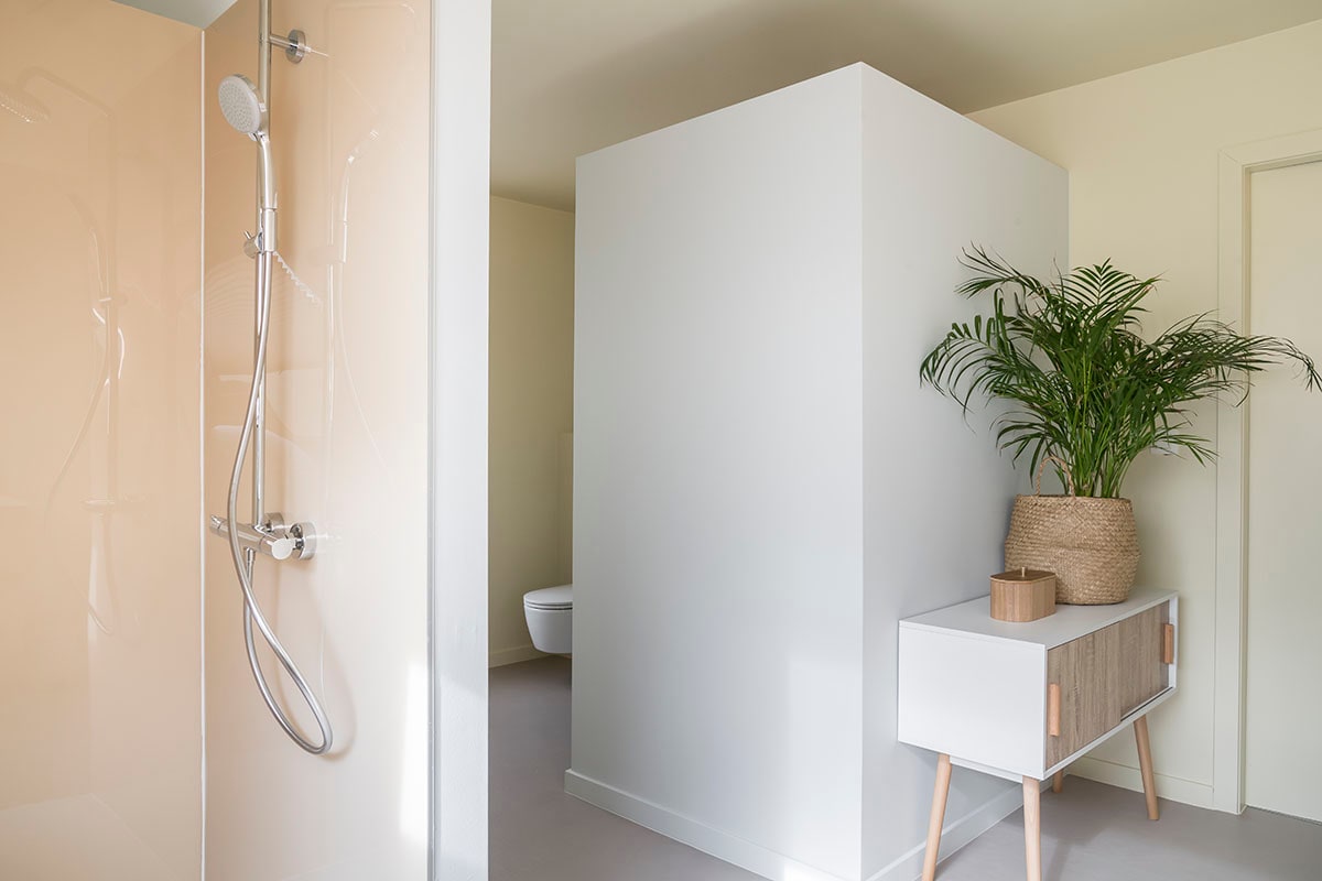 Wandbekleding douche: Panelle – Pergamon (Duscholux bij ). Kraanwerk douche: Croma 160 (Hansgrohe bij ). Lage kast wit/hout (privébezit).