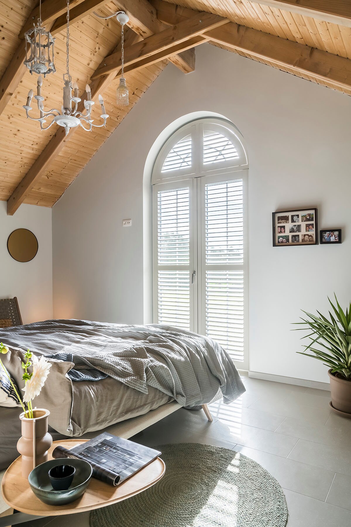 Primewood shutters – 0452 cream grey (). Bed – Fly (Velda), rond tapijt (Kave Home), bruine vaas en groene schaal (HKliving), dekbed (vtwonen collectie), grijze sprei (Vandyck), blauwe sprei (Heckett &amp; Lane), spiegel (Woood).