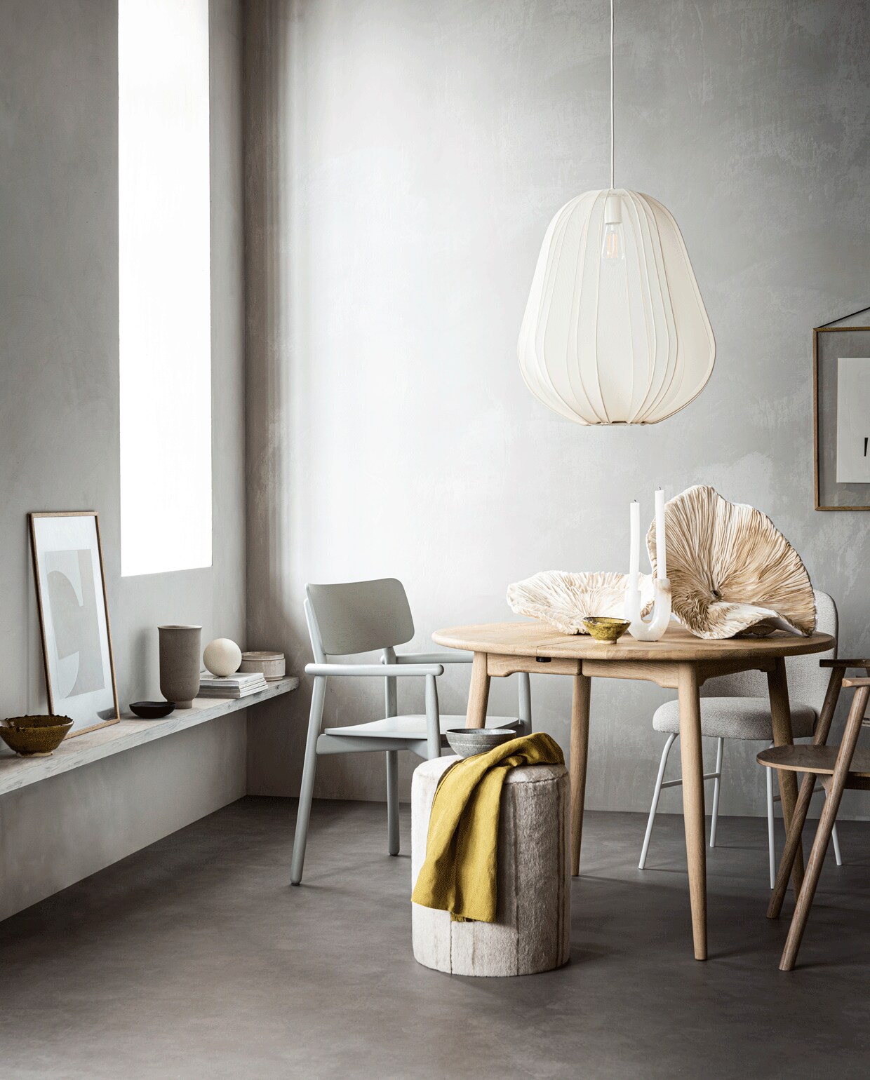 Muurverf kleur North (bauwerkcolour.com). Vloer Novilon kleur Beton van vtwonen, 200 cm of 400 cm breed, exclusief installeren (vtwonen.be/vtwonen-collectie). Ronde eikenhouten tafel (coosdewitwonen.nl). Zachtgrijze houten eetkamerstoel (letoile.store). Gestoffeerde eetkamerstoel met witte poten Aleta van Viccarbe (designtales.nl). Witgelakte eikenhouten eetkamerstoel, hanglamp 60×53,3 cm (hxØ) (bolia.com). Poef grijze craquelé schaal met witte streep (covanderhorst.nl). Kunstobjecten in zwamvorm gemaakt van moerbeipapier (elsavisser.com). Vaalgele keramieken schaal, marmeren kandelaar met kleurschakeringen (loods5.nl). Vaalgele theedoek (maisonnl.com). Eikenhouten lijst (letoile.store). Poster Deconstructed no. 34, 29,7×42 cm (ateliercphshop.dk). Op de plank: vaalgele keramieken schaal, zandkleurige pot met deksel (loods5.nl). Poster Object blanc no. 25, 40×30 cm (ateliercphshop.dk). Eikenhouten lijst (letoile.store). Zwart houten schaaltje (loods5.nl). Grijze vaas van Menu (designtales.nl). Witte bol (covanderhorst.nl). Overig privébezit.
