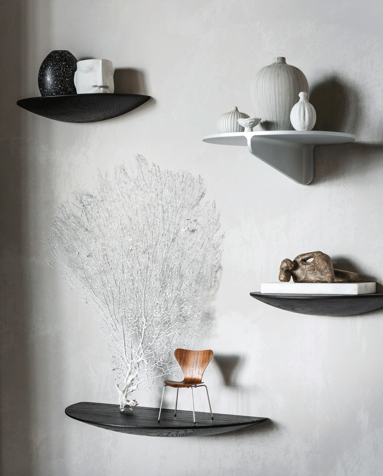 Muurverf kleur North (bauwerkcolour.com). Zwarte houten wandplanken van Menu, maat M, maat L (vtwonen.be). Metalen wandplank Museum (stringfurniture.com). Witte porseleinen mok met gezicht van Gloria Landenberger (studiosomee.com). Kleine vaas met strepen, grote vaas met strepen, handgemaakte vaasjes (letoile.store). Walnoothouten miniatuur vlinderstoel, beeld op marmer van Dominic Lansen (coosdewitwonen.nl). Overig privébezit.