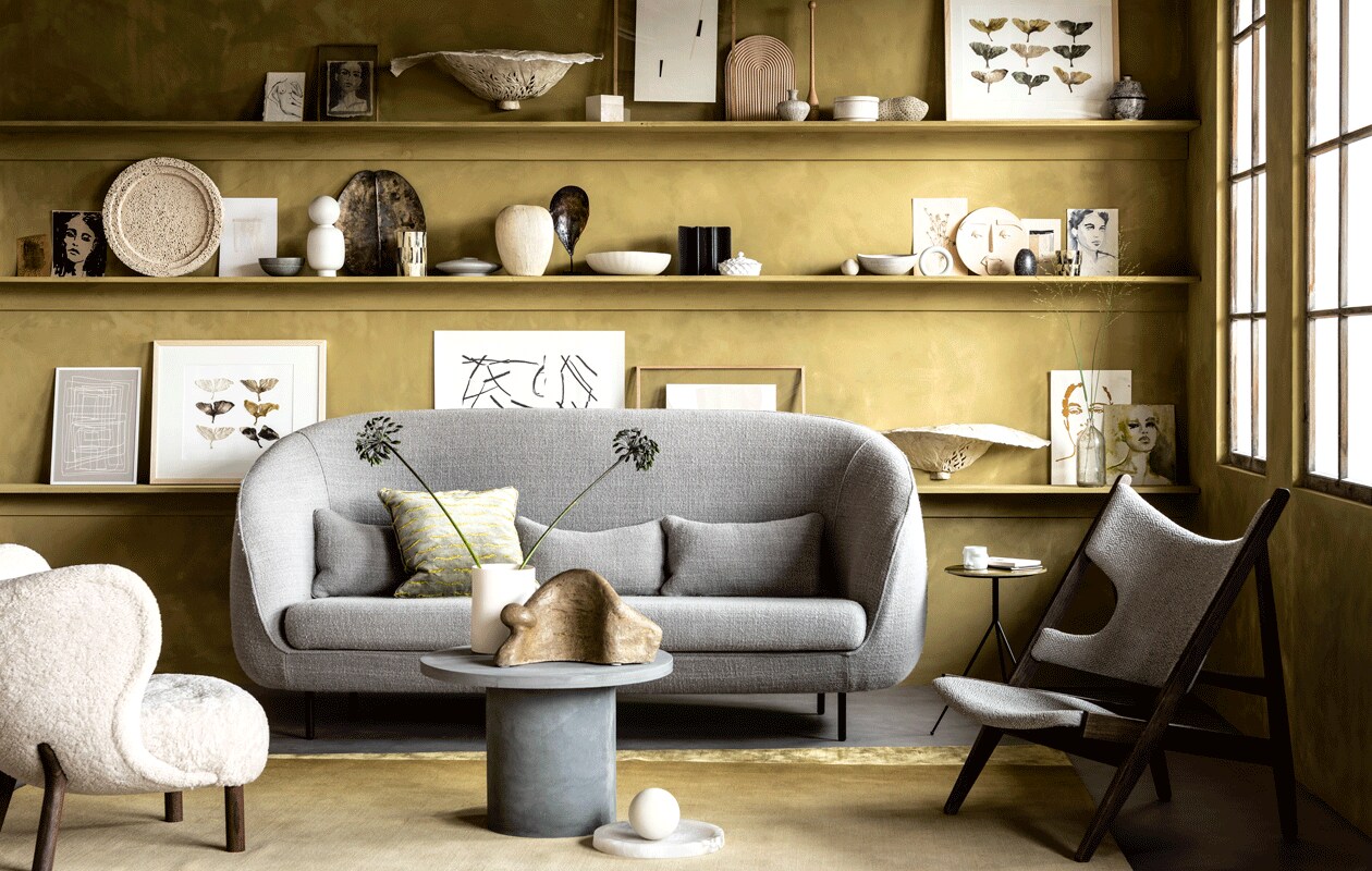 Muurverf kleur Seagrass (bauwerkcolour.com). Vloer Novilon kleur Beton van vtwonen, 200 cm of 400 cm breed exclusief installeren (vtwonen.be/verkoopadressen). Witte fauteuil, kussen (mobilia.nl). Zetel Haiku van Fredericia, 228x88x104 cm (bxdxh), houten fauteuil met gestoffeerde zitting Knitting Chair, ronde marmeren schaal Circular bowl van Menu (designtales.nl). Tapijt, bijzettafel driepoot witte cilindervaas, witte bol (covanderhorst.nl). Ronde betonnen salontafel van House Doctor (vtwonen.be). Beeld van Dominic Lansen, (coosdewitwonen.nl). Witte porseleinen mok met gezicht van Gloria Landenberger (studiosomee.com). Op de bovenste plank: geschilderde schetsen en schilderijen, (tinystories.nl). Kunstobject in zwamvorm gemaakt van moerbeipapier, wandobject met gekleurde ginkobladeren van moerbeipapier in lijst (elsavisser.com). Eikenhouten lijst, vaasje (letoile.store). Poster Deconstructed no. 34, 29,7×42 cm (ateliercphshop.dk). Houten plank in regenboogvorm van Hay (vtwonen.be). Ronde porseleinen opberger met deksel, beige object met bruine vlekjes (loods5.nl). Zwart beschilderde porseleinen pot met deksel (maisonnl.com). Kegel privébezit. Op de middelste plank: geschilderde schetsen, schilderijen en collages (tinystories.nl). Witte ronde stenen schaal, grijze craquelé kom met witte streep, witte schaal witte craquelé schaal (covanderhorst.nl). Witte vaas met ronde bol, lichtgrijze houten cirkel van Hay (vtwonen.be). Dienblad in vorm van blad, hoge waxinelichthouder in zwart en parelmoer, zandkleurige vaas met gestreepte textuur, schelp op statief, lage theelichthouder met kleurschakeringen van zwart en parelmoer (loods5.nl). Zwart object en opberger Wave (coosdewitwonen.nl). Wit porseleinen schaaltje met deksel (maisonnl.com). Rond keramieken masker van Gloria Landenberger (studiosomee.com). Op de onderste plank: poster Deconstructed no. 43, 29,7×42 cm, poster Deconstructed no. 31, 50×70 cm poster Object blanc no. 25, 40×30 cm (ateliercphshop.dk). Lijsten van wit en blank eikenhout (letoile.store). Wandobject van moerbeipapier met gekleurde ginkobladeren in lijst (elsavisser.com). Geschilderde schetsen, schilderijen en collages, (tinystories.nl). Overig privébezit.