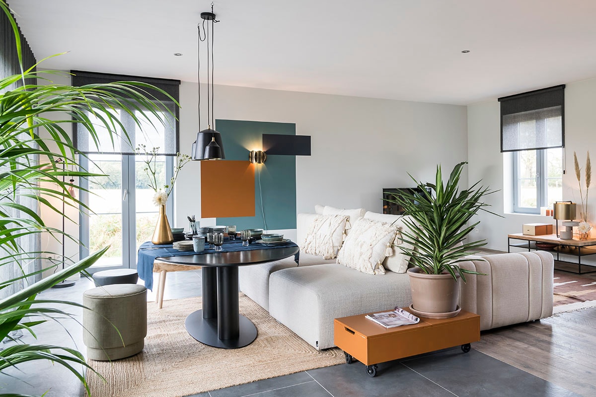 Hanglampen (Lifestyle), vloerlamp (ETH York), wandlamp (Dutchbone), poefs Xavio – 2 tegen elkaar (), kussens op poef (Riverdale), tafel Buddha Dining (), poef (vtwonen collectie), kruk (Woood), tapijt (Riverdale), tafelloper (DDDDD Kit), vaas (Dutchbone), bijzettafel op wieltjes (Woood).